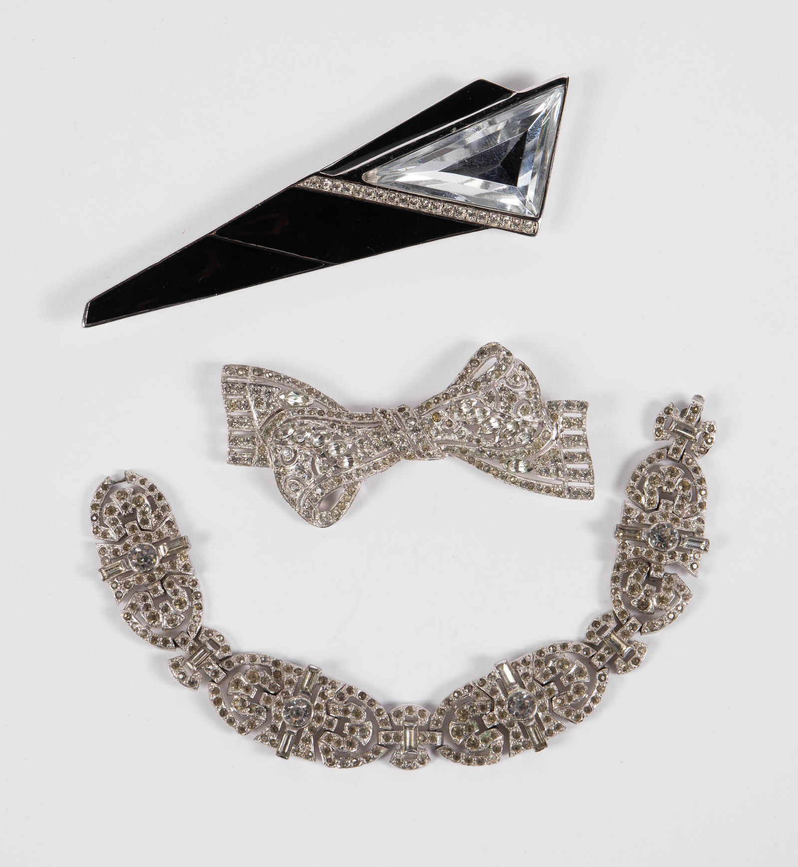 3 Vintage Trifari Pieces - KTF & Kunio Matsumoto: The lot contains 3 vintage Trifari jewelry pieces. First, there are two rhinestone pieces, a bracelet and a bow brooch, marked KTF. The last piece, a brooch with a large triangular rhinestone and blac