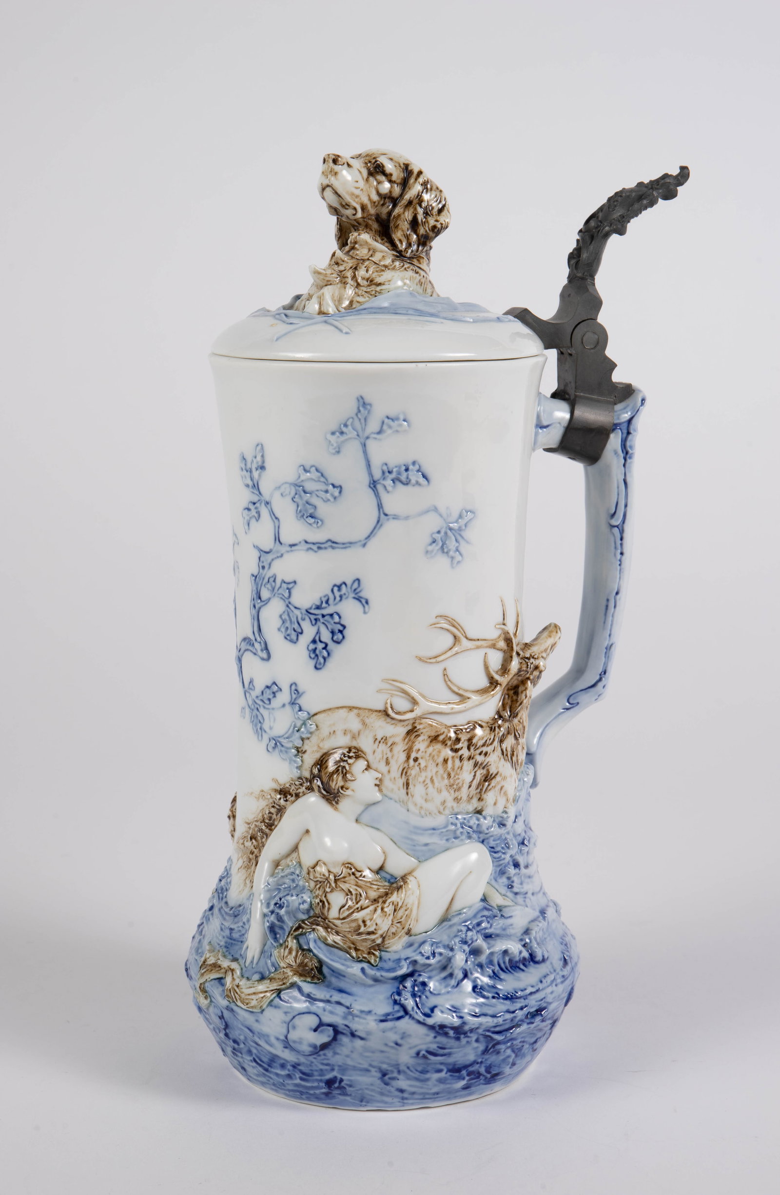 Antique Pate-sur-Pate Porcelain Stein with Elk.: The Antique stein is unsigned. It features a high relief design of a nude woman, an elk, and a dog in nature. The lid features a dog bust. The piece measures 10 1/2" x 4 3/8" x 5 3/4". The piece is in