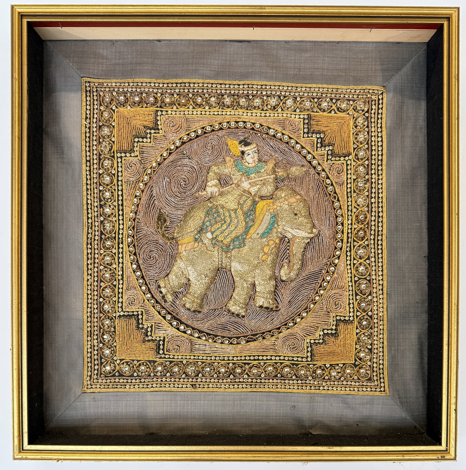 Burmese Kalage Tapestry, Framed.: The piece has sequins and gold-colored thread. There is one bead missing along the bottom circular border. The frame has a bit of gilt loss. Otherwise, the piece looks to be in good overall condition.