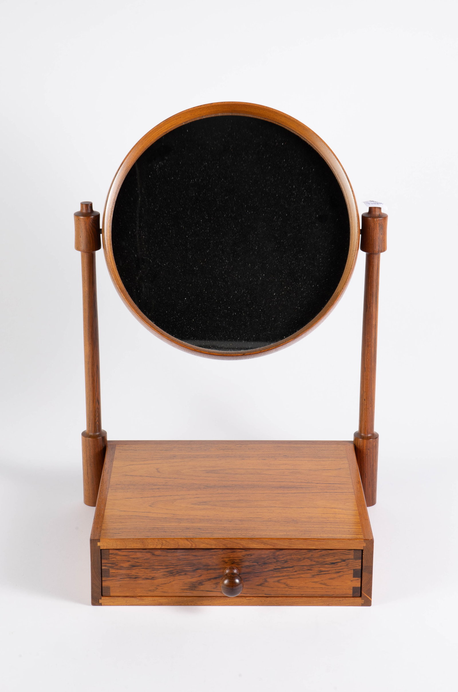 Rosewood Tilting Vanity Mirror w/ Attached Drawer.: The maker is unknown. The round mirror can tilt all the way around. Overall, the piece looks to be in very nice condition. The dimensions are 13 3/8" x 11" x 18". In-house shipping is available. Pleas