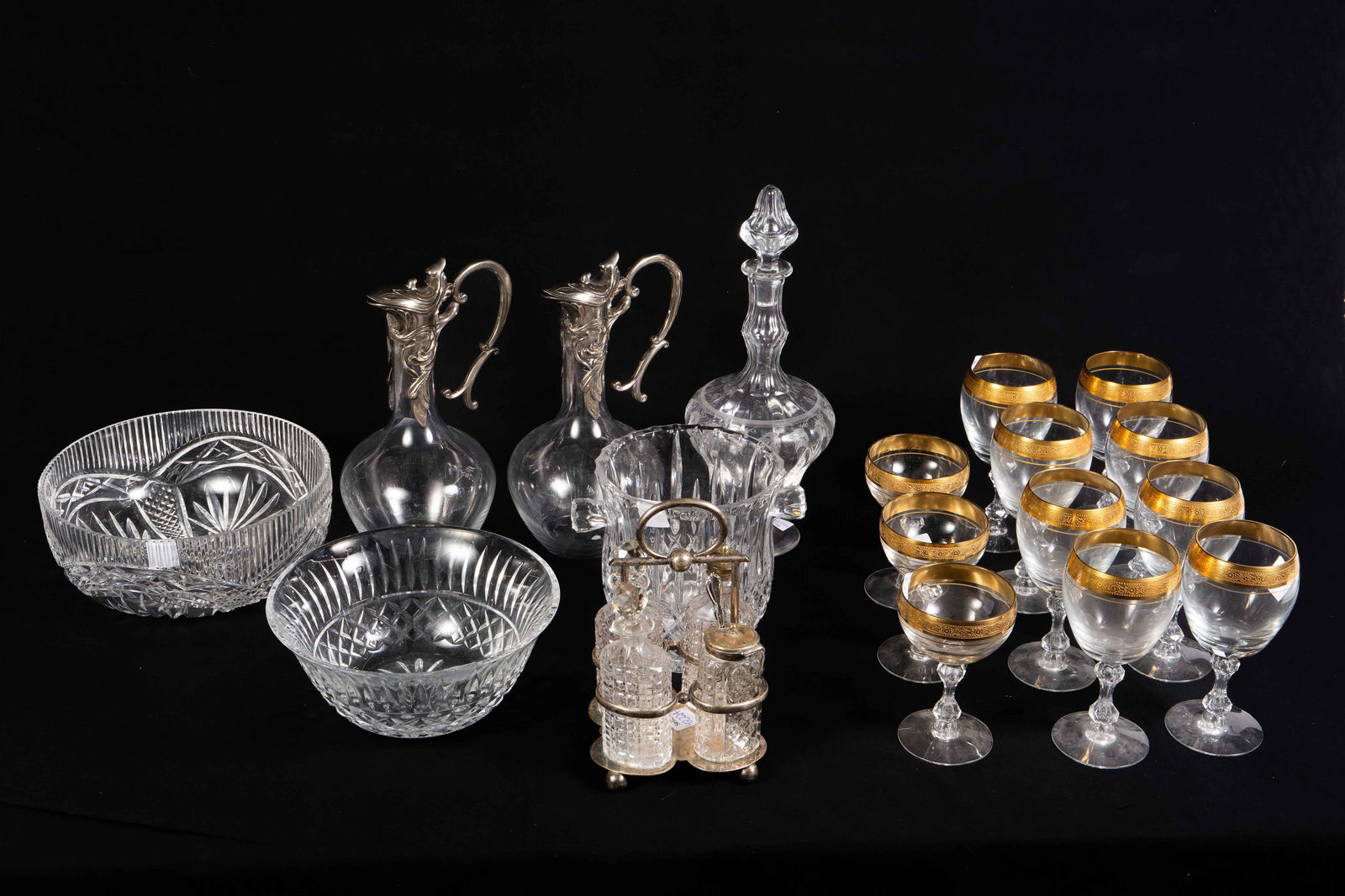 Lot: Cut Crystal, Gilt Stemware, Decanters, More.: The lot contains 18 items. There are 8 wine glasses and 3 sherbets with ornate gilded rims, a champagne bucket, a Waterford fluted bowl, a Waterford Salad bowl, a silverplate cruet set with 4 bottles,