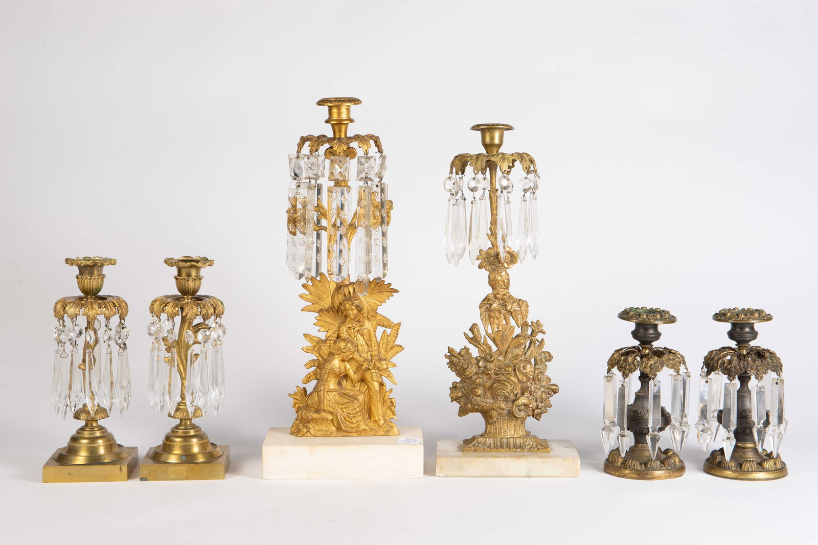 3 Pair of French Gilded Prism Candlesticks.: The lot contains 3 pairs of ornate French candlesticks with hanging crystal prisms. The tallest pair are gilded bronze, while the smallest pair is a bronze tone metal. The tallest pair have alabaster