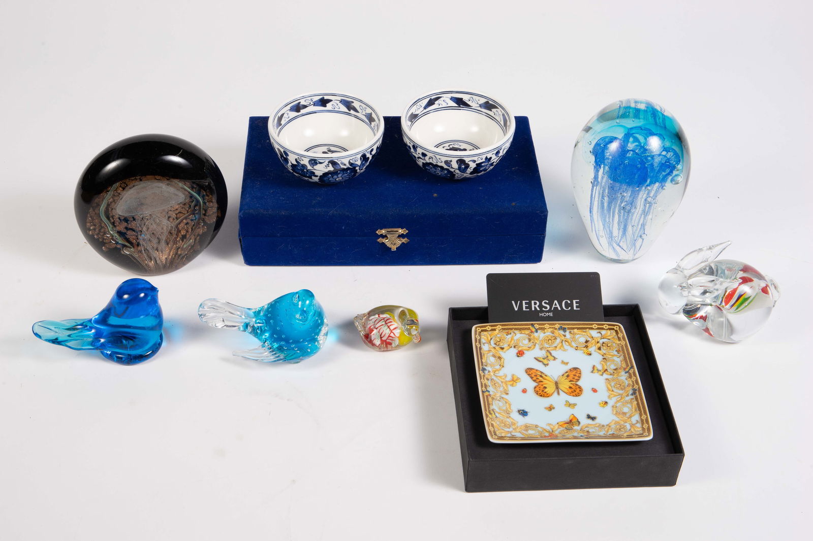 Lot: Versace Porcelain, Murano Glass, etc.: This lot includes art glass paperweights, a Versace butterfly canape plate with box, and a pair of Turkish bowls with storage box. Overall, the lot looks to be in good condition. The largest item is t