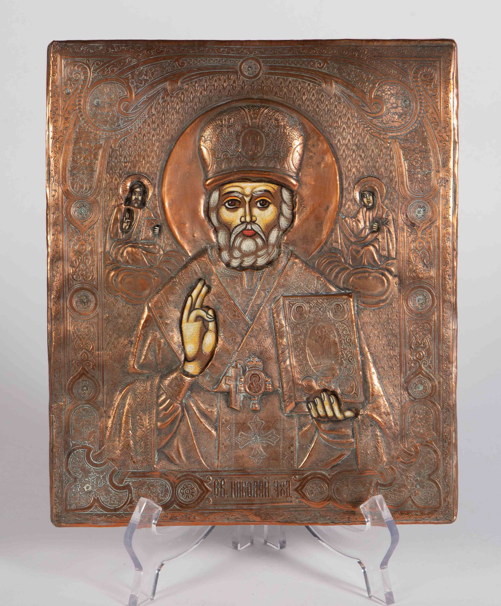 Russian Icon of St. Nicholas, Copper.: The antique Russian icon depicts St. Nikolai or St. Nicholas and a couple of other figures. It is engraved with writing under the central figure. The piece measures 10 1/8" x 8" x 1". There are some s