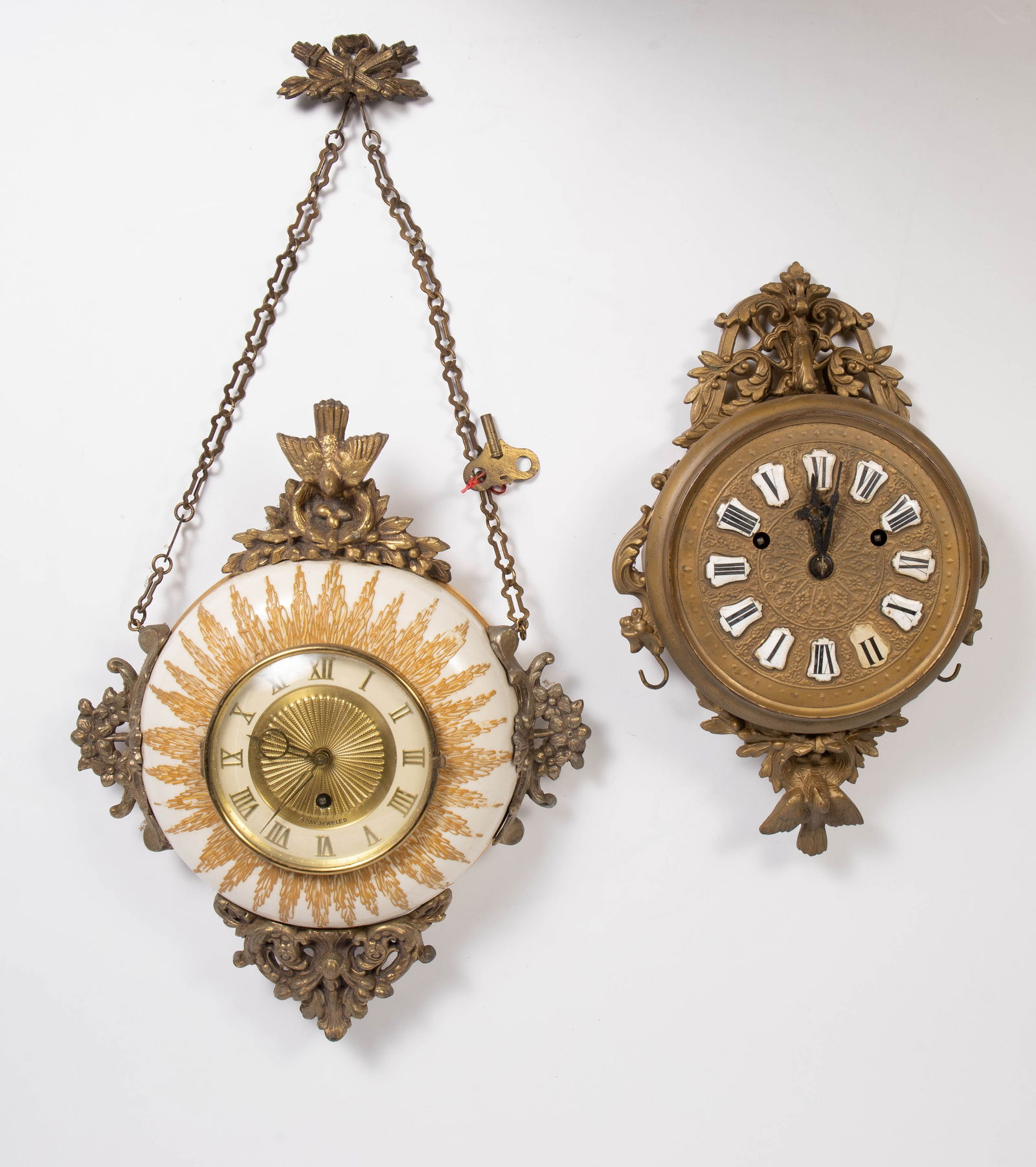 Lot of 2 Round Hanging Wall Clocks w/ Bird Motif.: Both are untested. The larger one comes with a key; it is an 8 Day Jeweled clock. It measures 11 3/4" x 3 3/4" x 14 3/4". The smaller clock measures 8 3/4" x 3 3/8" x 14 3/8". Both show some scratches