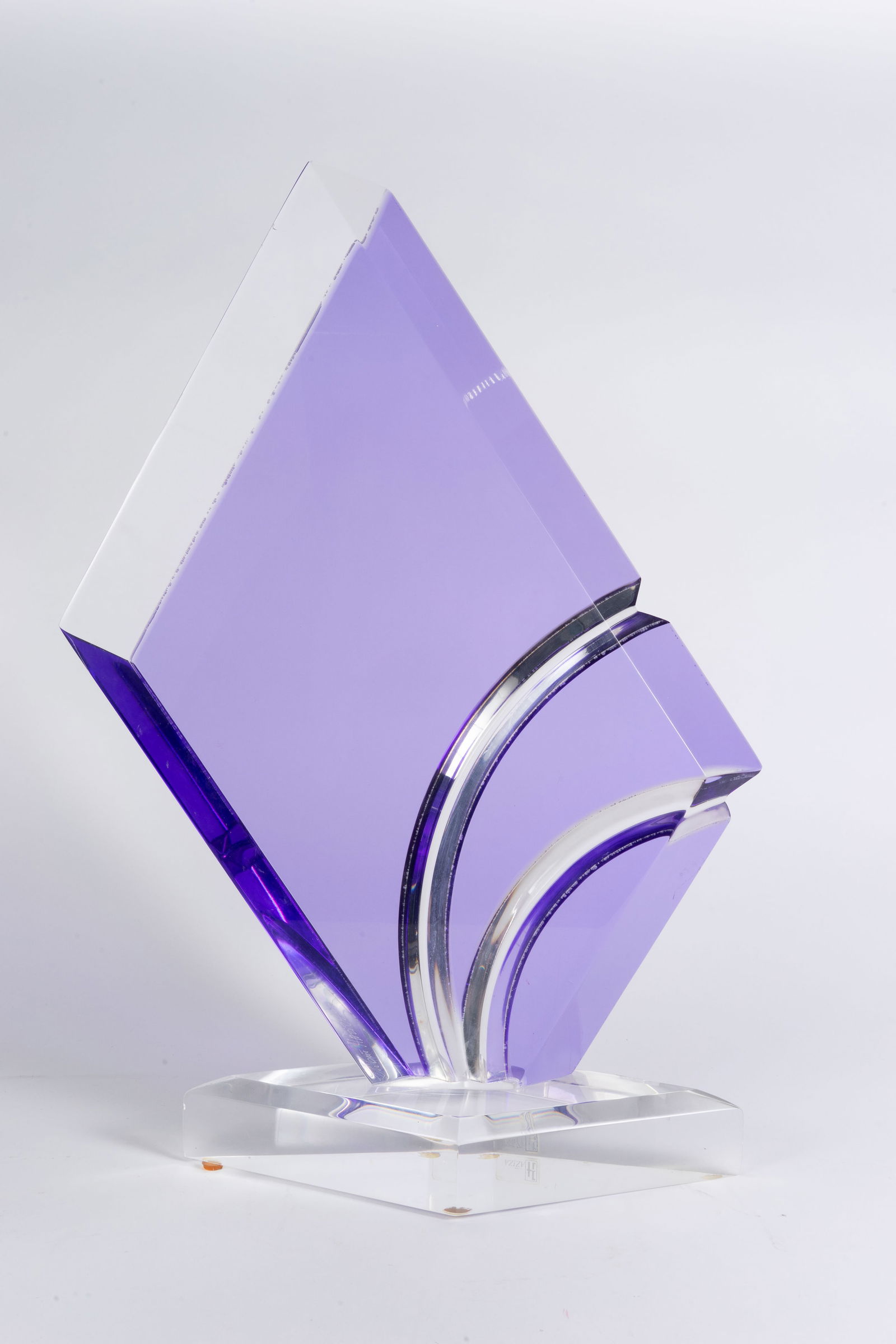 Shlomi Haziza Acrylic Abstract Sculpture, Purple.: The abstract lucite or acrylic sculpture features clear and purple or violet acrylic in a tall geometric shape, with curved line details. It has the Hazizia sticker on the base edge. The piece measure