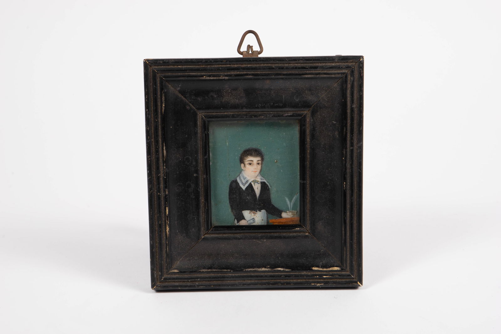 English Naive School Miniature Portrait of Writer.: The miniature portrait depicts a young man next to a desk holding a rolled piece of paper and an inkwell with quill pens in it. The black frame measures 5 1/2" x 5 1/8", and the sight size measures 2