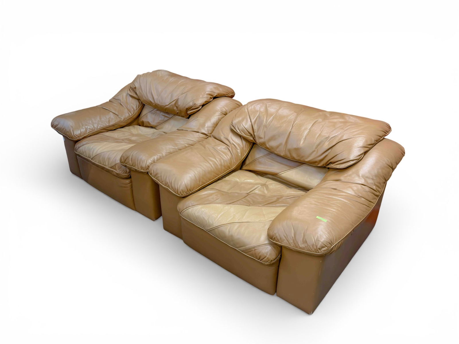 Pair of Vintage Leather Lounge Chairs, Tan / Camel: The pair of vintage oversized chairs feature dark tan or camel toned leather, with light beige piping on most of the chairs. The seats and inner back feature a diagonal color block design, with three