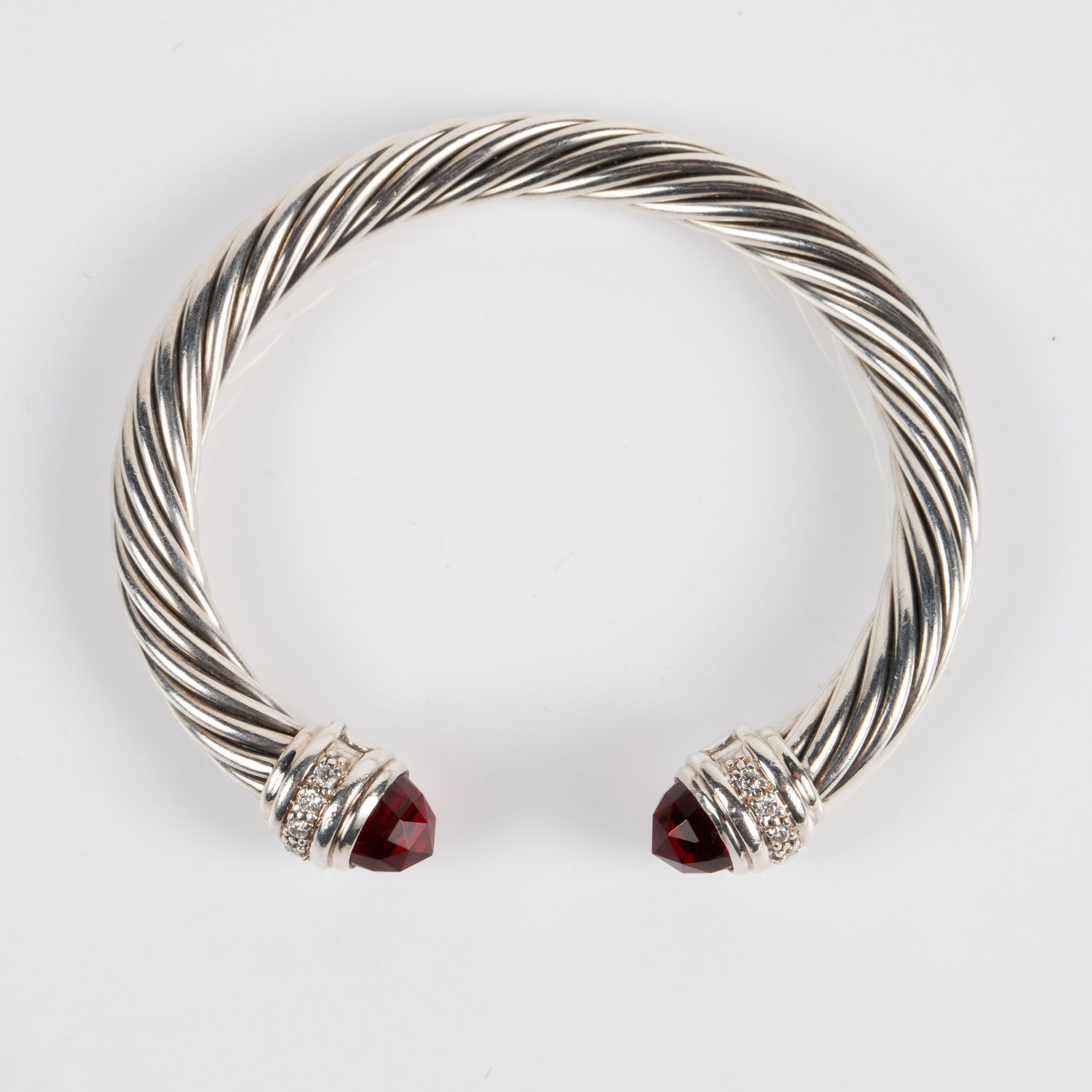David Yurman Sterling, Garnet & Diamond Cuff.: The designer cuff bracelet has a rope design with multifaceted red garnet stones at the ends. Both ends are marked 925 / D.Y., and feature a row of small round brilliant diamonds. It measures 2 1/8" a