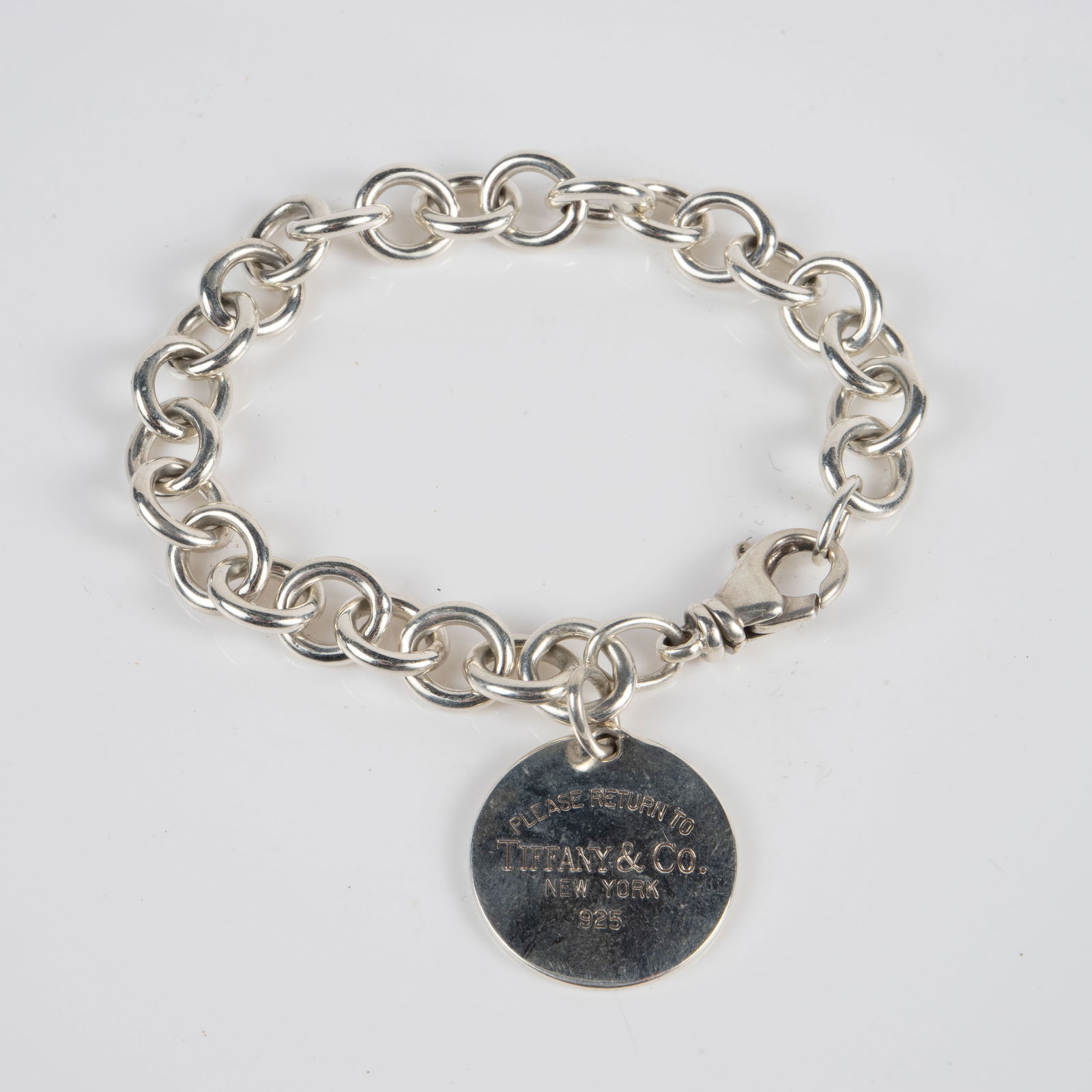 Return to Tiffany & Co. Sterling Charm Bracelet.: The bracelet has a Please Return to Tiffany & Co. New York 925 round charm on it, and the clasp is marked 925. It measures 7 1/2" long, 3/8" wide, and the charm measures 7/8" in diameter. The piece we