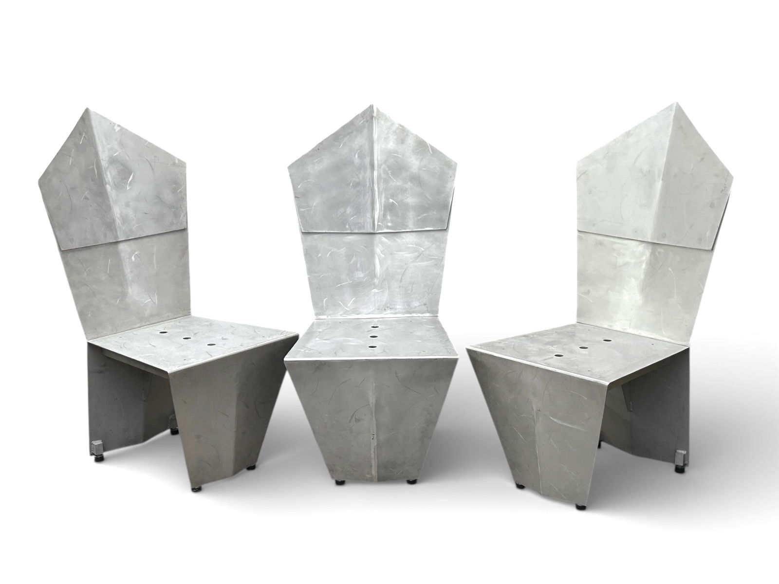 3 Silver Post Modern Aluminum Architectural Chairs: The lot contains 3 postmodern geometric architectural chairs. They feature a pentagon shaped back and a brushed silver color finish. The seats have 3 decorative circular holes (possibly for outdoor dr