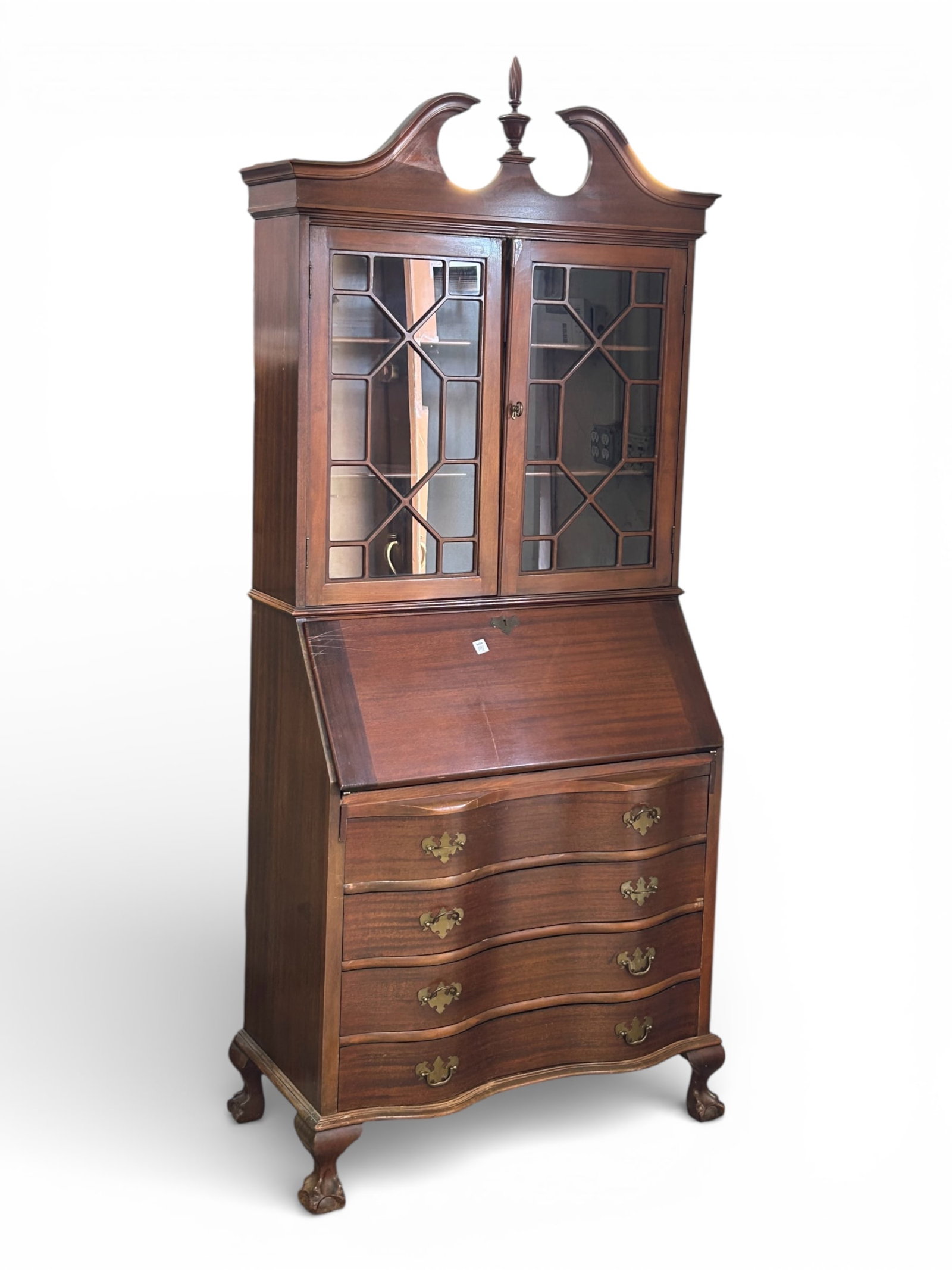 Antique Mahogany Secretary Desk.: This Chippendale style desk has two doors with fretwork overlay, two fixed interior shelves, brass hardware, a crest with a finial, a dropfront writing surface, four large lower drawers, and carved