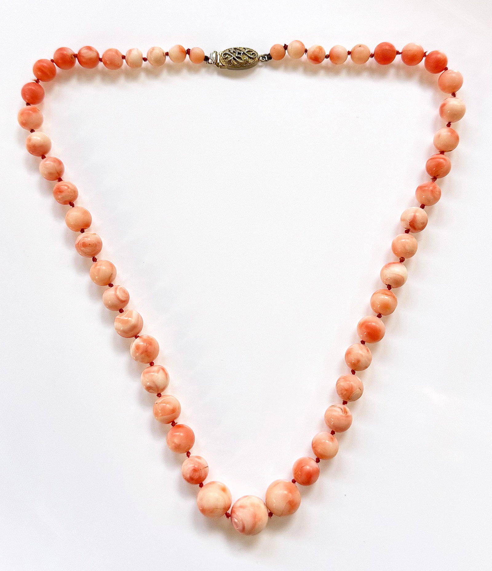 Vintage Angel Skin Coral Necklace w/ Silver Clasp.: The graduated beaded coral necklace has an ornate clasp marked Silver. The beads measure from 6mm - 12mm in diameter. The necklace measures 18" long, and weighs 1.625 Oz. Troy, or 50.5 Grams (includin