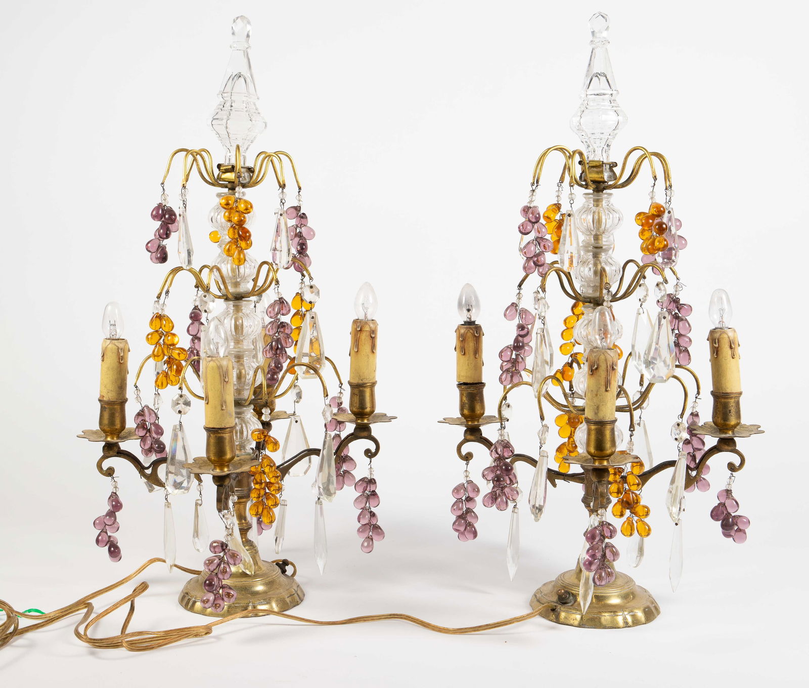 Pair of Girandole Lamps w/ Glass Grape Clusters.: Each lamp has four electric candle lights, dangling prisms, and purple and amber glass grape clusters. There are some scratches and signs of surface wear, and one of the finials is a bit wobbly. The