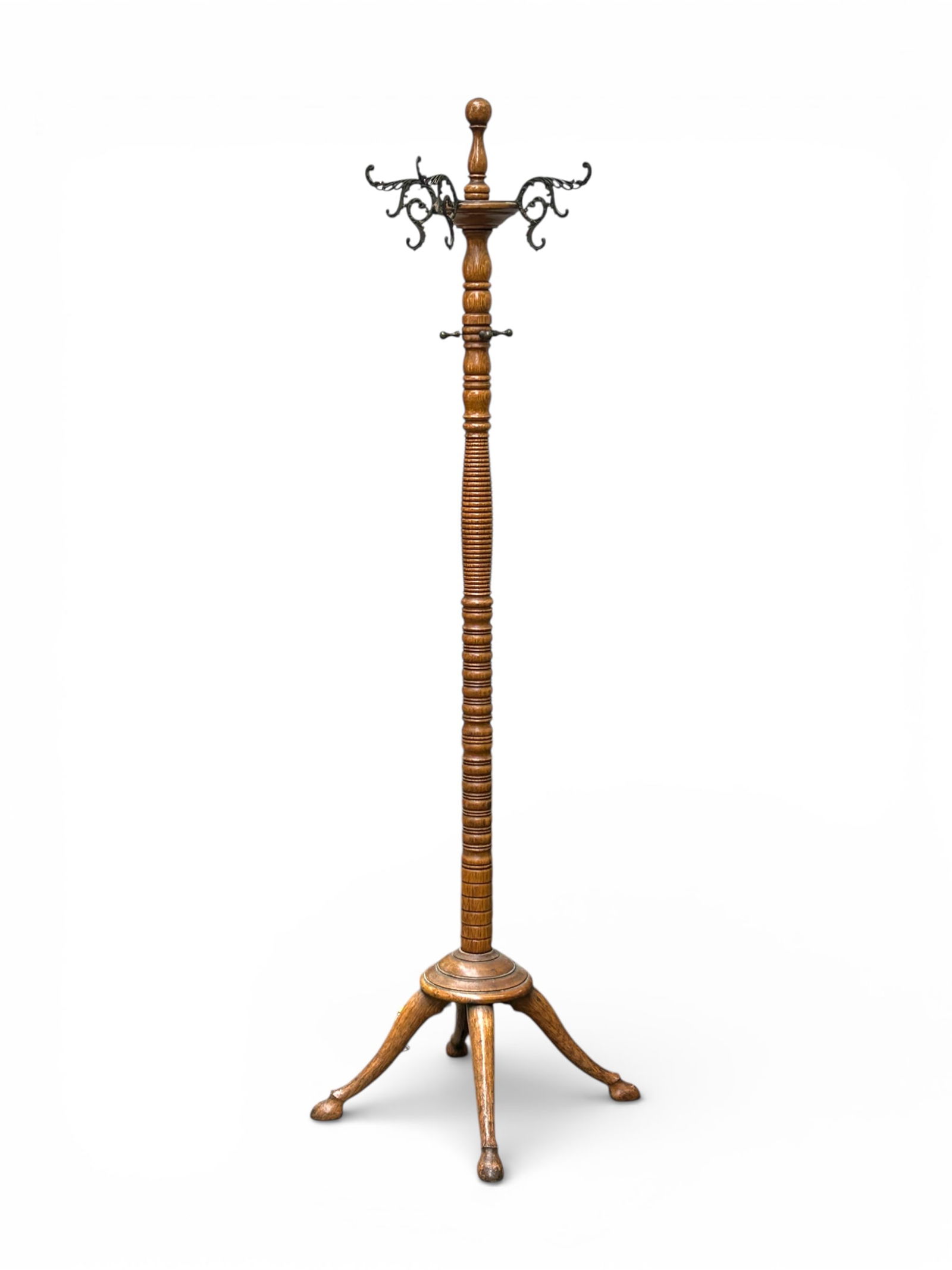Antique Oak Coat Rack.: This elegant piece has a turned stem with four legs, and ornate iron hooks for hanging. Below the main hooks are four additional metal nubs. One of the main hooks is missing, but otherwise, the piece