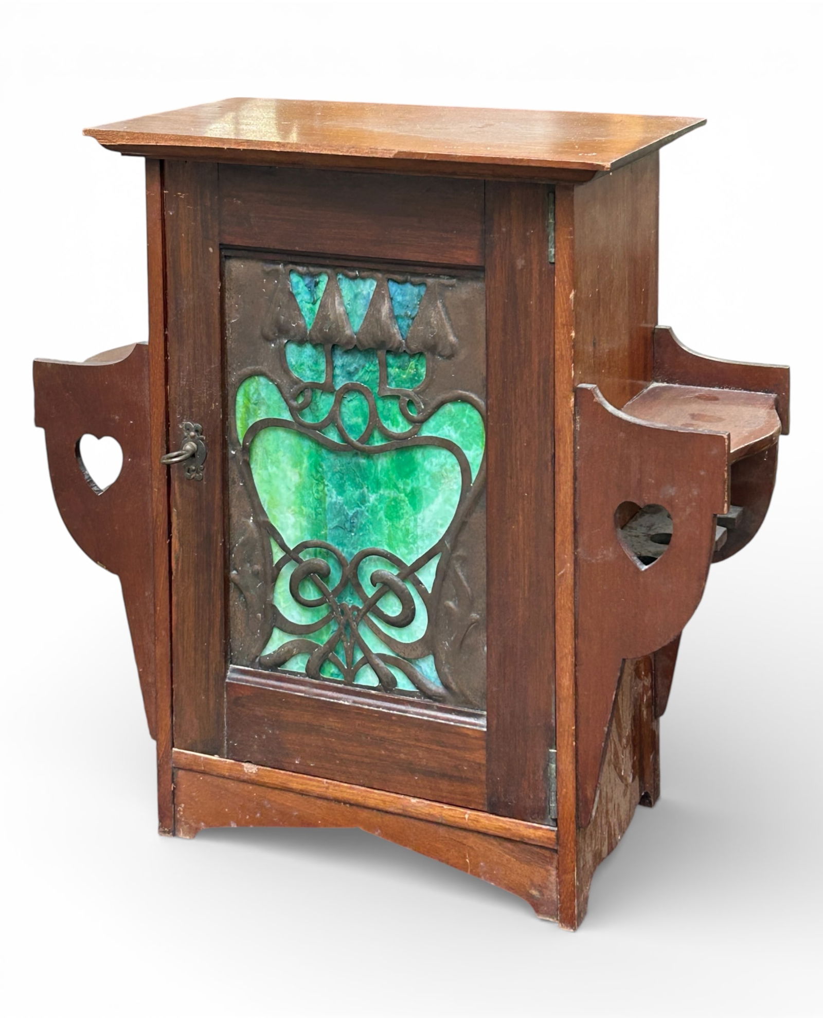 Arts & Crafts Smoker's Cabinet w/ Slag Glass.: The cabinet door has a green slag glass front with a decorative metal (copper ?) grill. Inside are two fixed shelves. There are additional shelves on either side of the door that have heart carvings.
