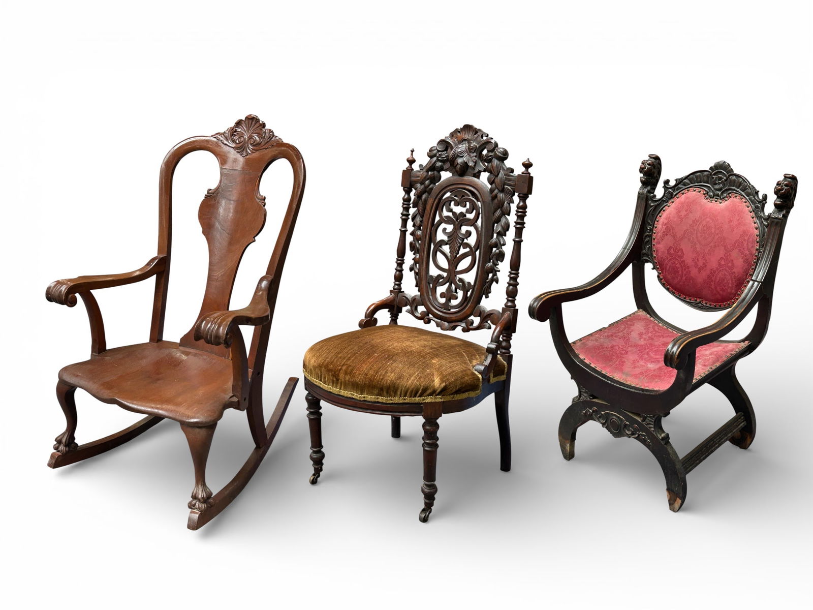 Lot of Two Victorian Chairs & One Rocker, As-Is.: The first chair is a Renaissance revival style chair with carved lion heads and other carvings. It is very wobbly, the right arm is broken, and the upholstery is dirty. The legs look water damaged,