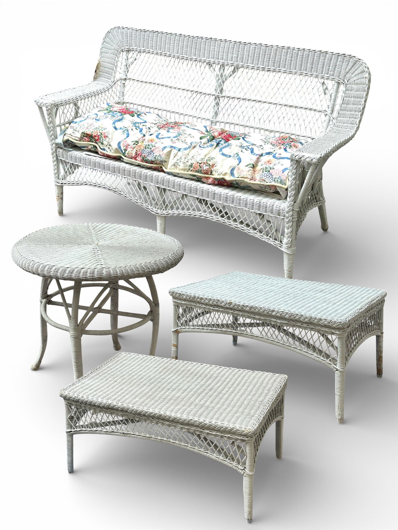 White Wicker Sofa & Three Tables.: The sofa has a removable floral upholstered seat cushion, wide armrests, and a high back. There are also two coffee tables and a round lamp table. There are some small broken areas on the wicker, but