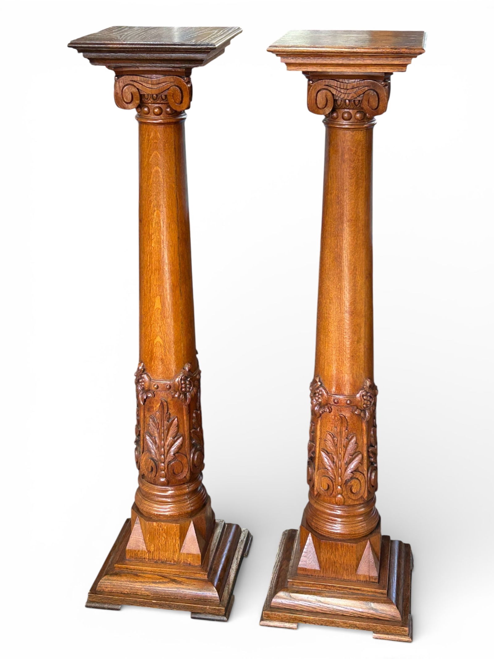 Pair of Carved Oak Columns.: These beautiful columns or pedestal stands have carvings of acanthus leaves, grapes, and more. Both are in good condition. Each column measures 14" wide, 14" deep, and 54" tall. The top surface area