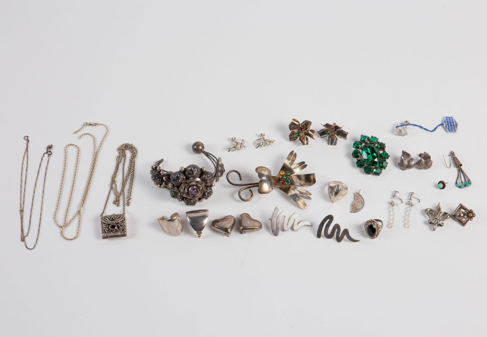 Lot of Sterling Silver Jewelry - Mexico, Locket.: The lot contains 16 pieces of sterling silver jewelry and a broken chain. There is a brooch and earrings set with multicolored stones, 6 pairs of earrings, a brooch with green crystals, a ring, a pend