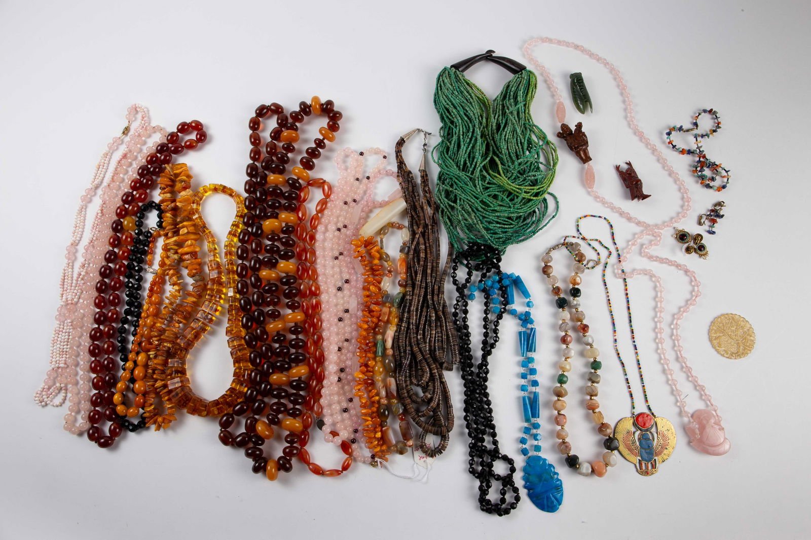 Mostly Stone Jewelry - Amber, Carved Quartz & Jade: The lot contains 30 pieces of costume jewelry. There are mostly necklaces, carved soapstone, a pair of earrings, a varied stone earrings and necklace set, a carved spinach jade cicada figure, and a ca