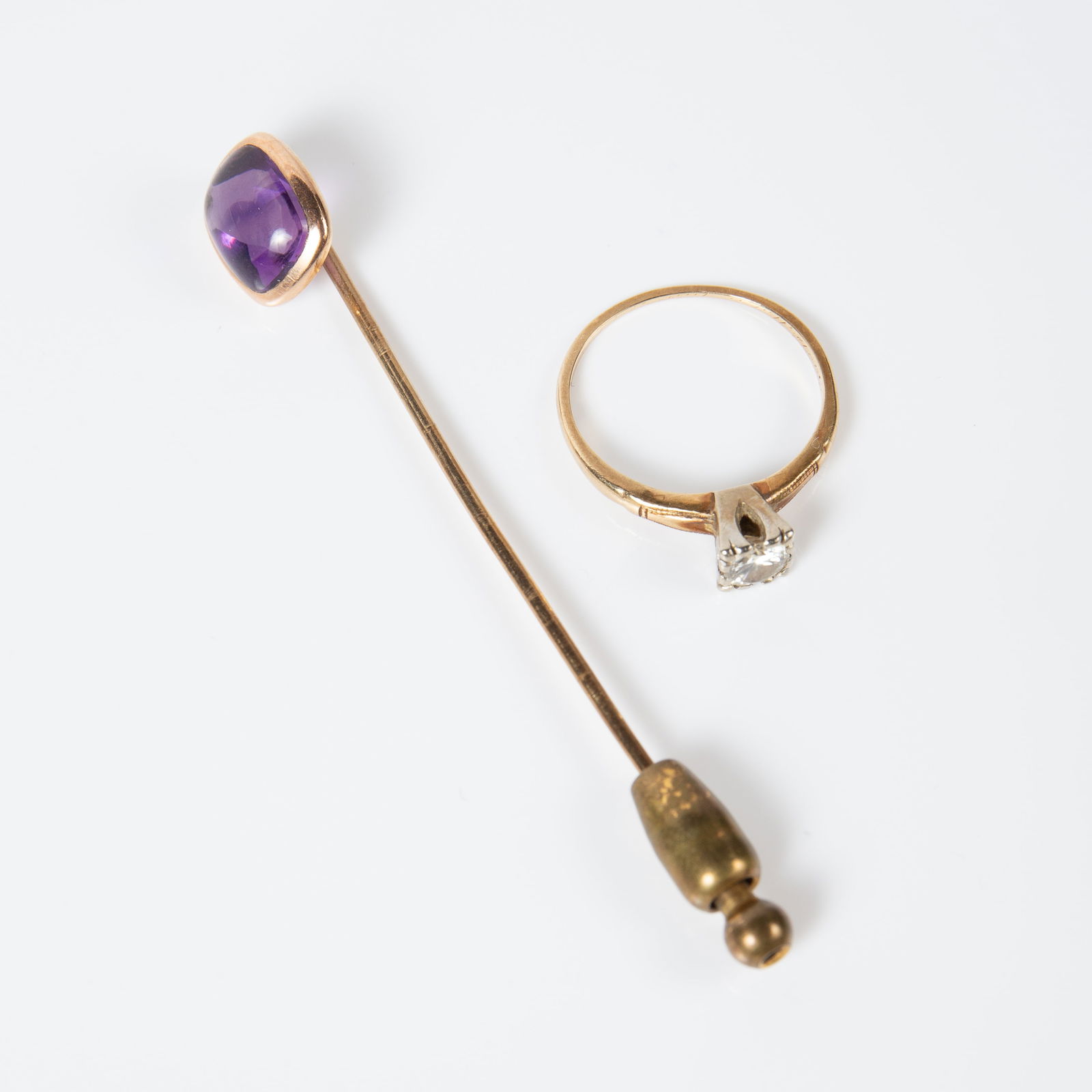 14K Gold Diamond Ring & Amethyst Stick Pin.: The lot contains 2 pieces of vintage or antique jewelry which are marked 14K. There is an engagement ring with a round brilliant diamond in a square setting. The ring is a size 7, and the diamond meas