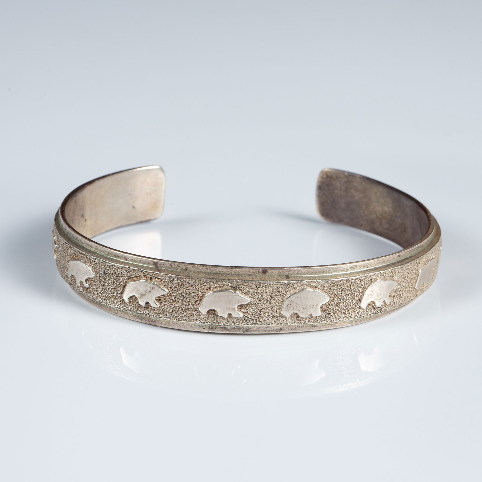 Ben Nighthorse Sterling Cuff Bracelet w/ Bears.: This solid sterling silver cuff bracelet by Ben Nighthorse Campbell features Native American bear silhouettes on a textured background. The piece measures 2 9/16" across the inside, and 11mm wide. It