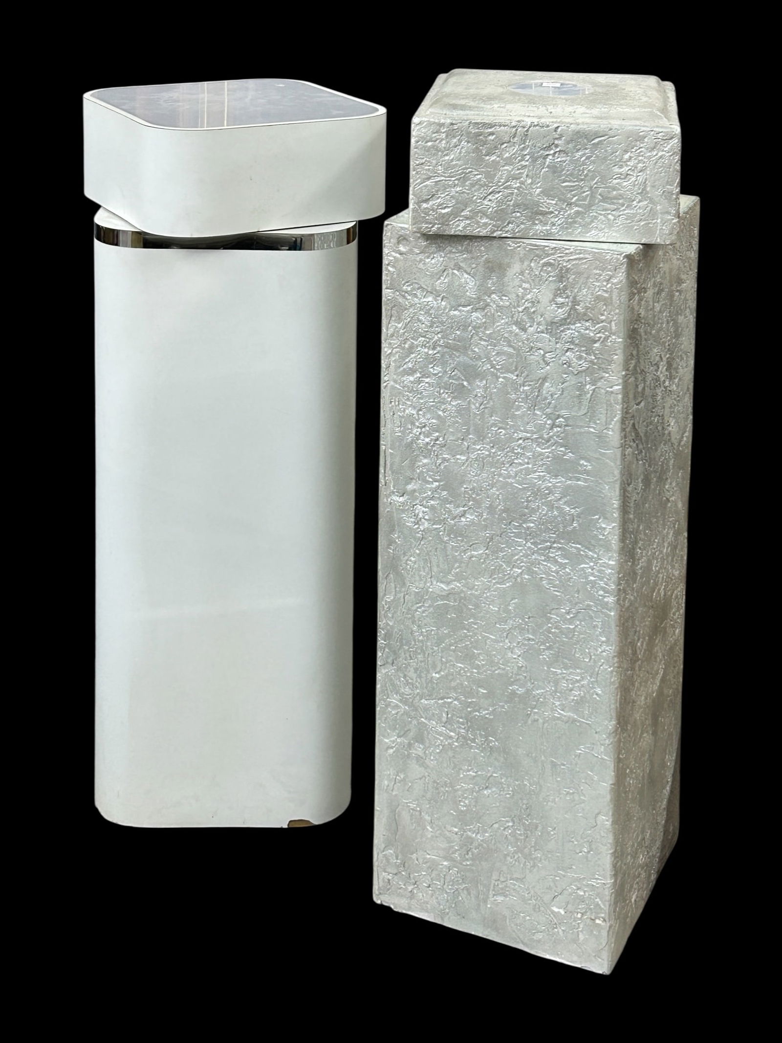 Two Pedestals with Rotating Tops.: This lot consists of a white pedestal which has chrome banding and a rotating top with an internal light. The other pedestal is silver colored, and is made of resin. It also has a rotating top, with