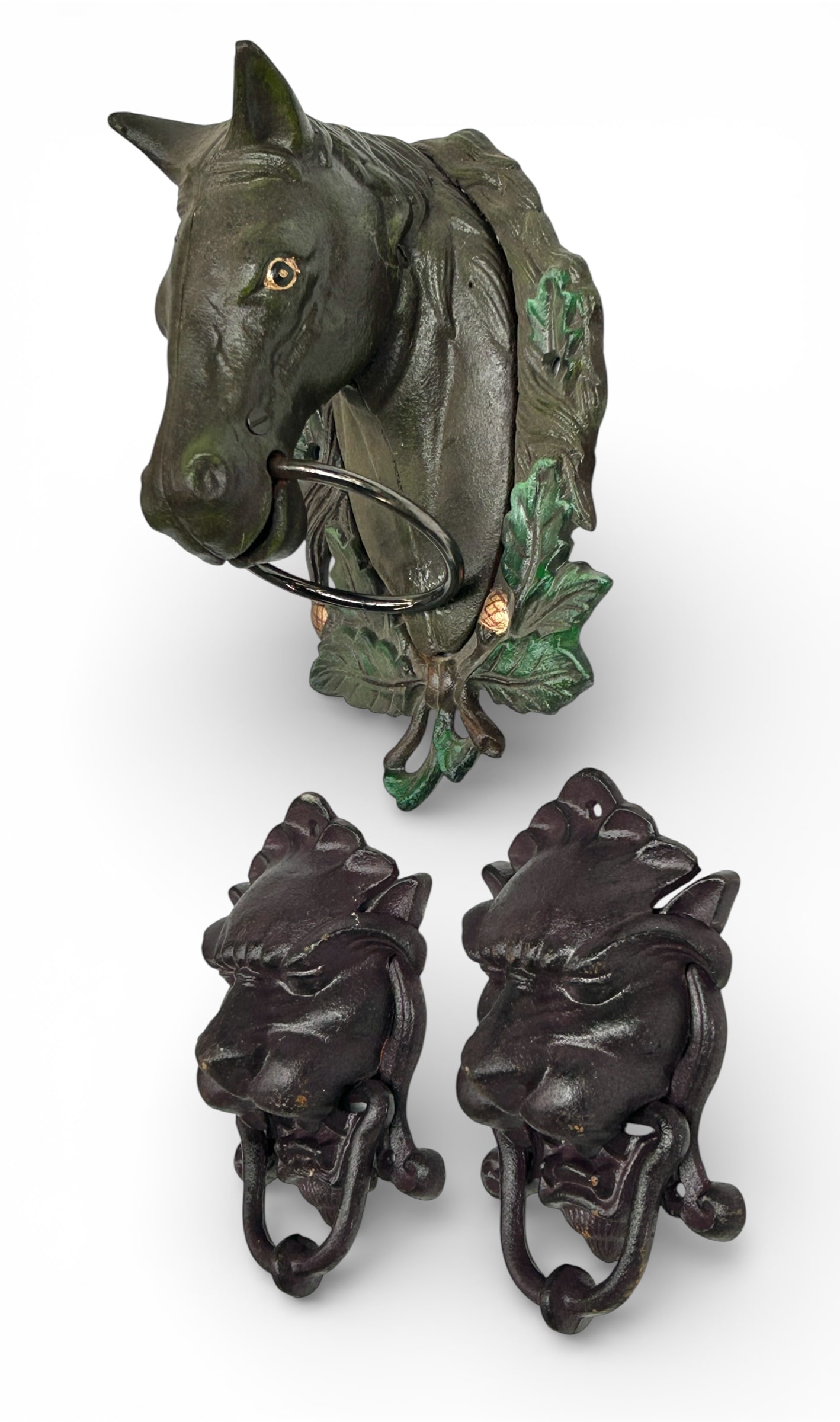 2 Painted Cast Iron Lion Head Door Knockers.: The pair of knockers are painted in a deep purple or violet. They measure 8 1/2" tall, 5 1/4" wide, and 3 1/4" deep. There are some scratches and stains on the items. Otherwise, the lot is in overall