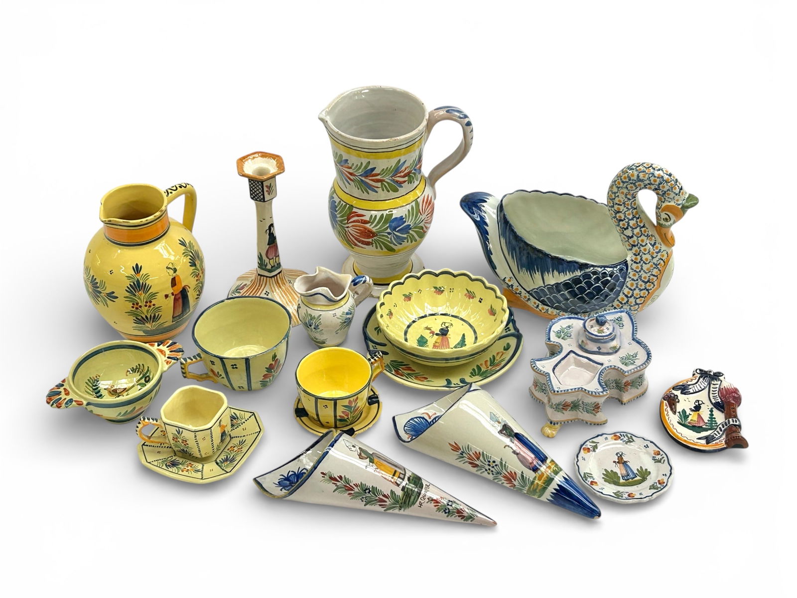 Lot of Henriot Quimper France Dishes & Decor.: This lot includes a swan bowl or vase, an inkwell, several teacups, a pair of wall pockets, two pitchers, and more. There are some nicks and other signs of surface wear, but overall, the lot looks to