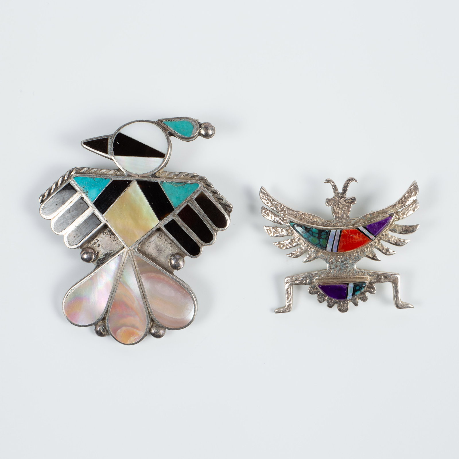 2 Native American Sterling Brooches Inc. C. Begay.: The lot contains 2 Native American Indian sterling silver brooches with inlaid stones. The smaller piece is signed CB Sterling for Calvin Begay, and the larger piece is etched XZP. Some of the stones