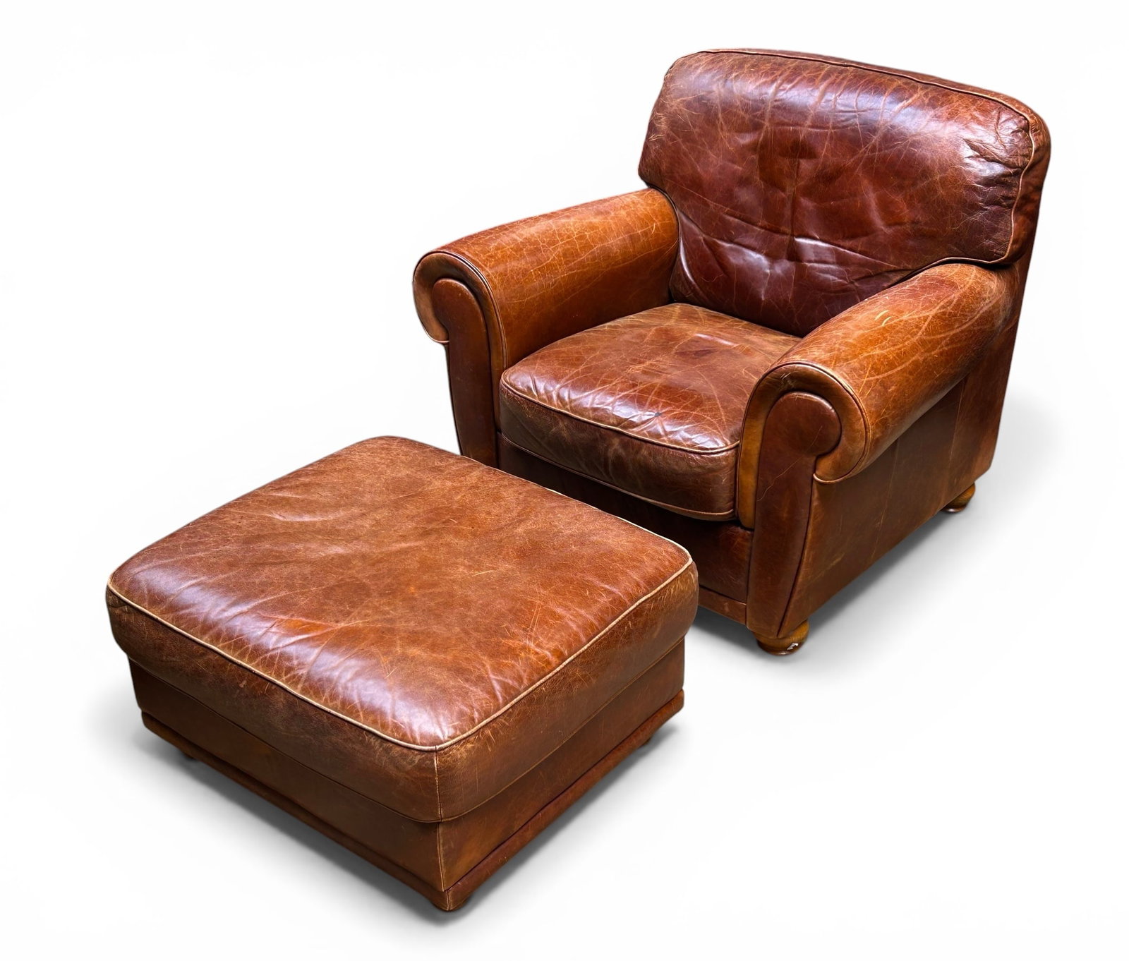 Vintage Brown Leather Roll Arm Chair & Ottoman.: The vintage natural leather lounge chair has stout turned wood legs. It measures 34 1/2" tall, 40" wide, and 37" deep. There are some stains, scratches, creases, and discoloration on the pieces. Other