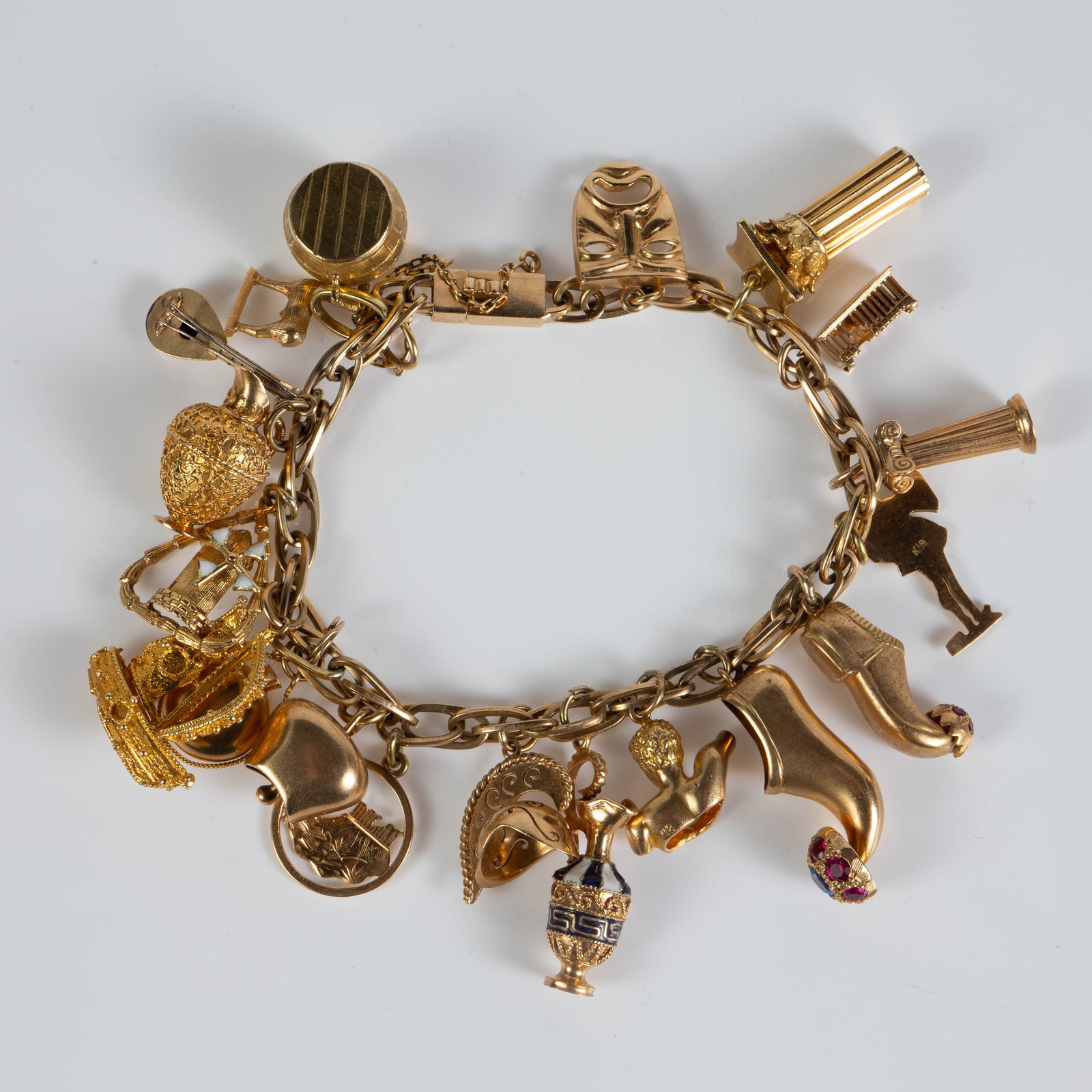 18K Gold Charm Bracelet w/ 19 Charms.: The bracelet is marked K18 on the clasp and on most of the charms. Eight of the charms are not marked, but most tested appropriately for 18K. A couple of the charms are 14K. The figures depicted on th