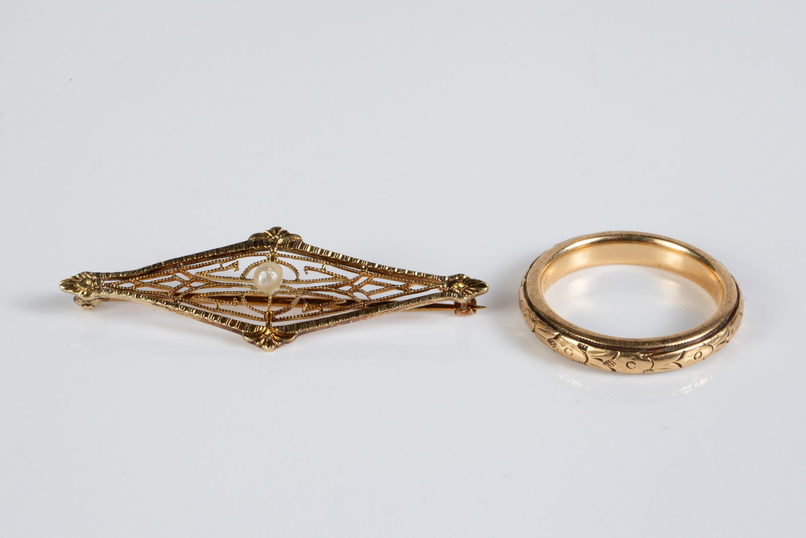 2 Pcs. Antique Yellow Gold Jewelry - 14K, 18K.: The lot contains 2 pieces of gold jewelry from the early 20th Century. There is an 18K gold etched wedding band marked Peacock 18K, and a 14K openwork brooch with a central seed pearl, which is marked