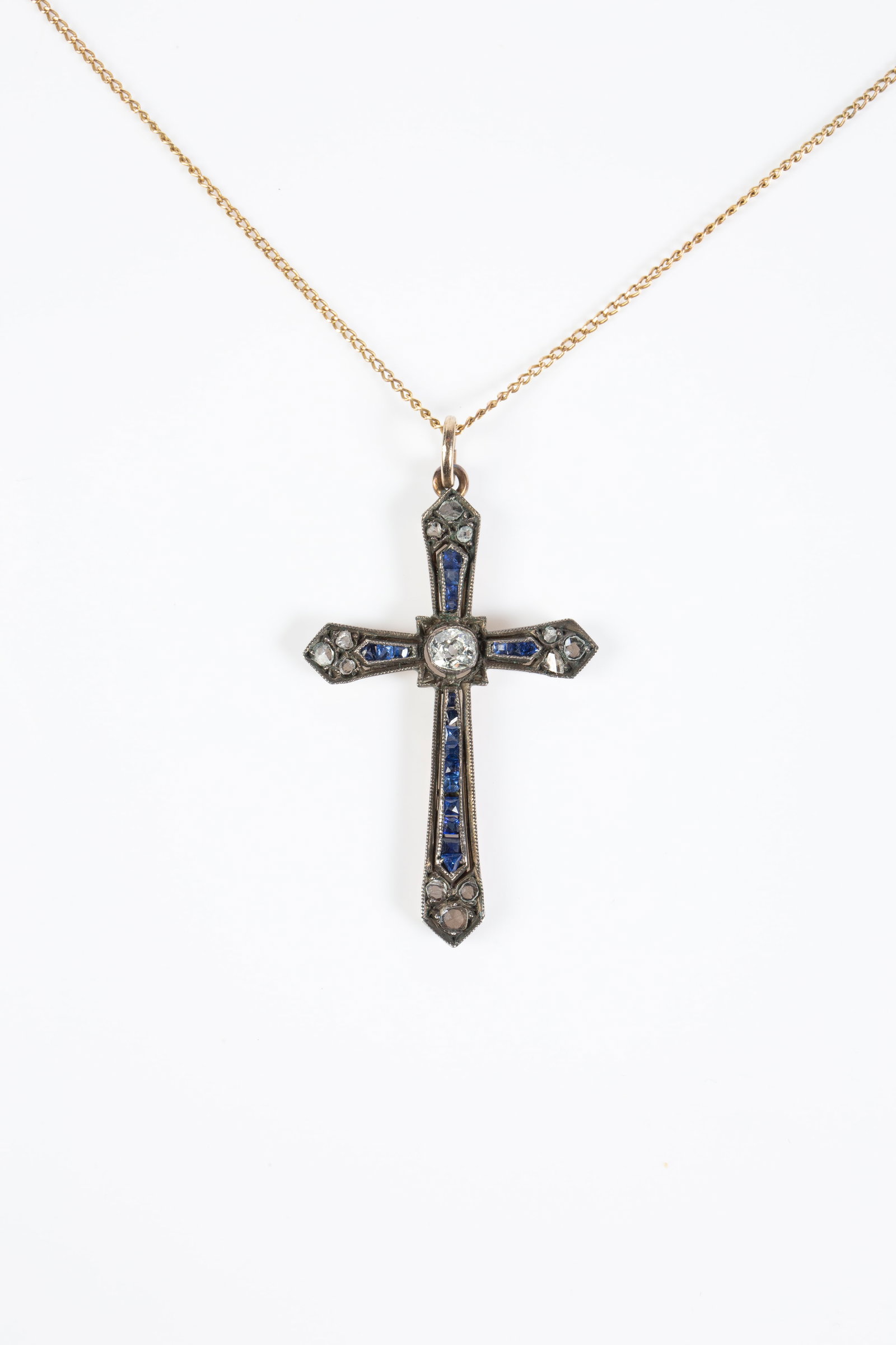 Antique 14K Gold & Silver Cross Necklace, Diamond.: The lot consists of a 14K gold necklace with an antique Art Deco cross pendant. The pendant has blue sapphire stones, a central mine cut diamond, and 12 rose cut diamonds. The largest diamond measures