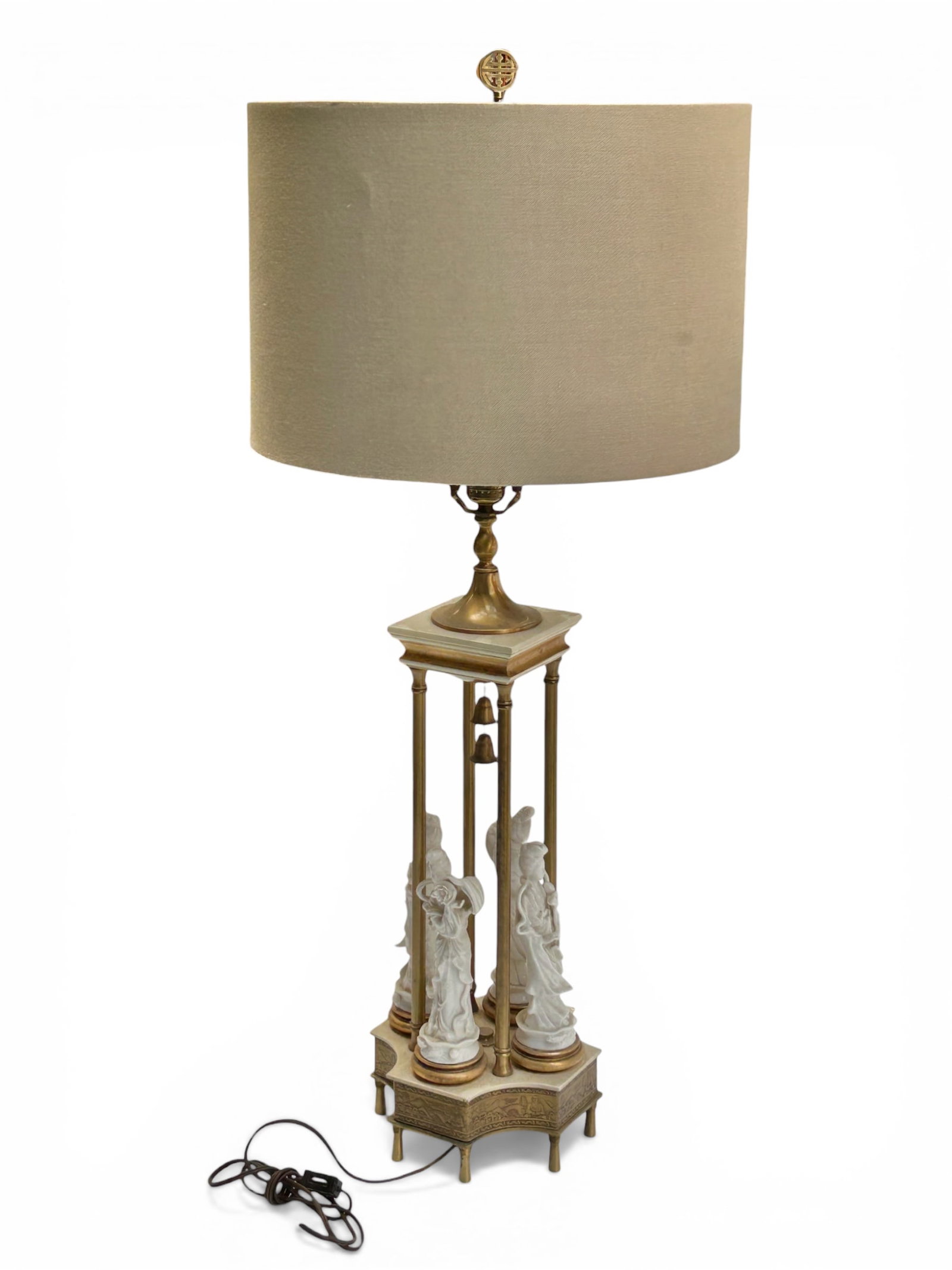 Asian Brass & Blanc de Chine Figural Lamp.: The tall lamp has a vintage Asian base with 4 Blanc de Chine porcelain figures, 4 brass columns, and a double bell at the center. The piece also has thick tooled repousse decorations of Buddha and oth