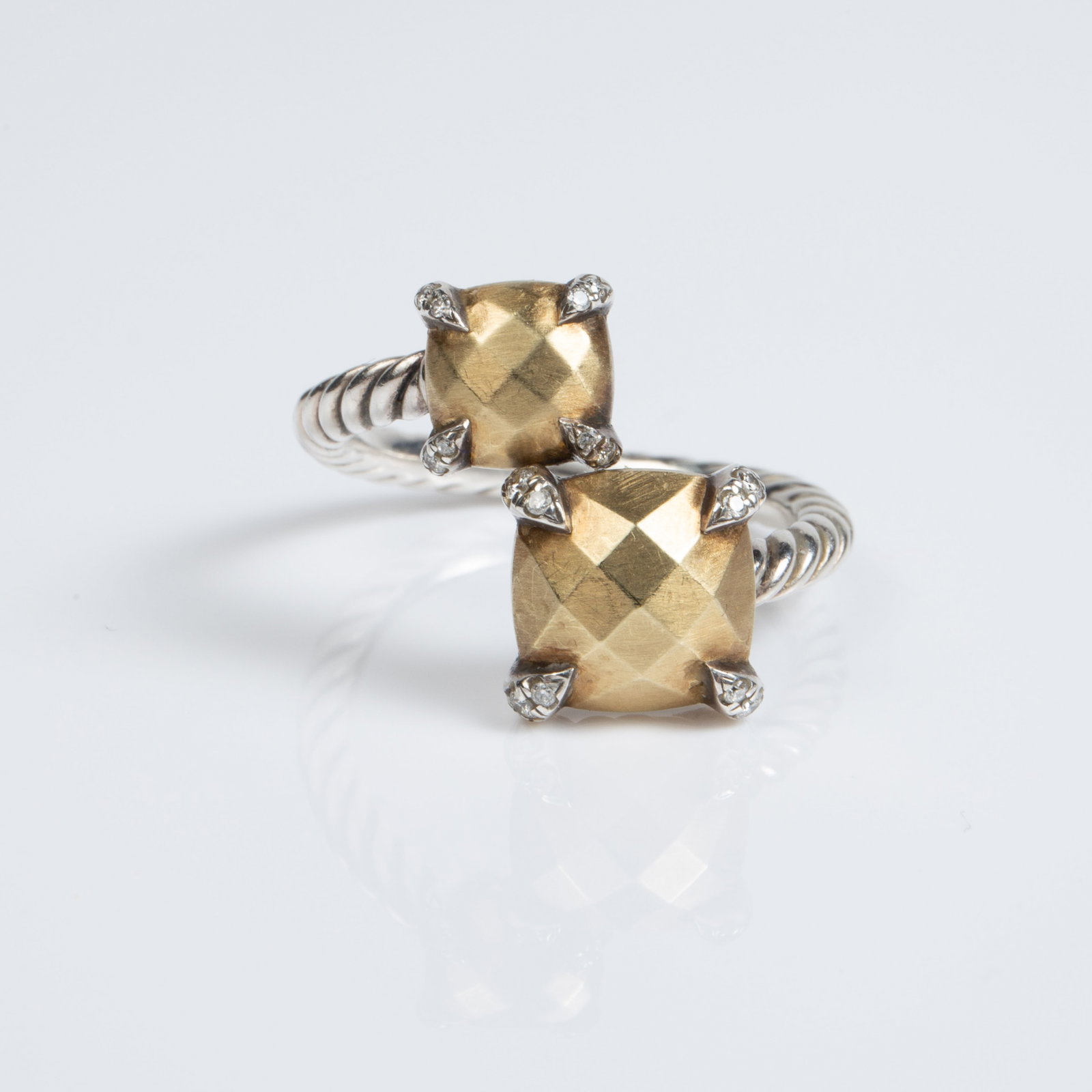 David Yurman Sterling, 18K, & Diamond Bypass Ring.: The ring is marked D.Y. 925 1/5 750.. The gold and silver ring boasts a cable band with two multifaceted cushion-cut style gold sections, having small round brilliant diamonds on the setting prongs. I