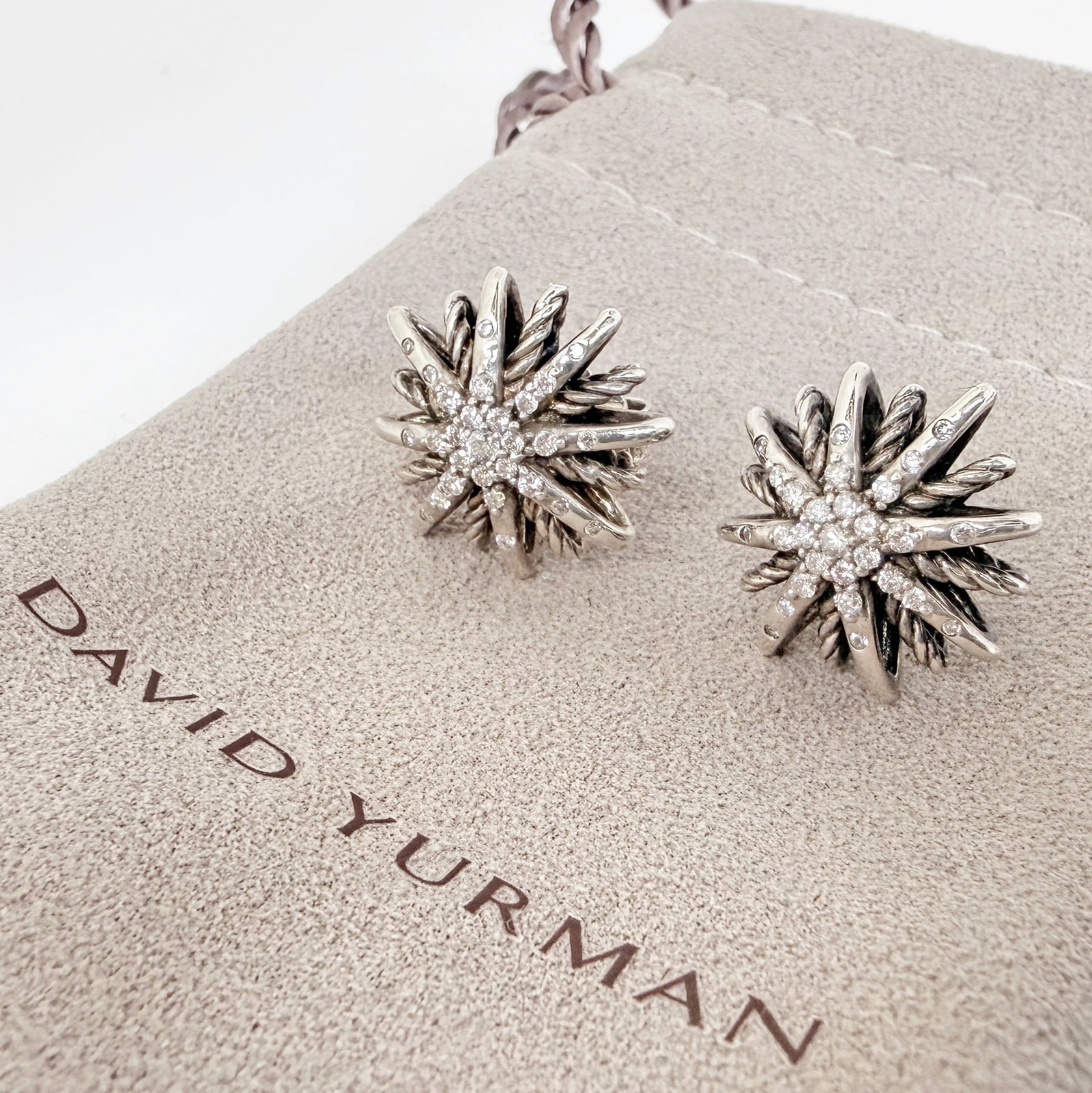 David Yurman Sterling & Diamond Starburst Earrings: The earrings depict a starburst design with small round brilliant diamonds radiating from the center. They are marked D.Y. 925 near the posts. They measure 16mm in diameter. They weigh 0.21 Oz. Troy, 