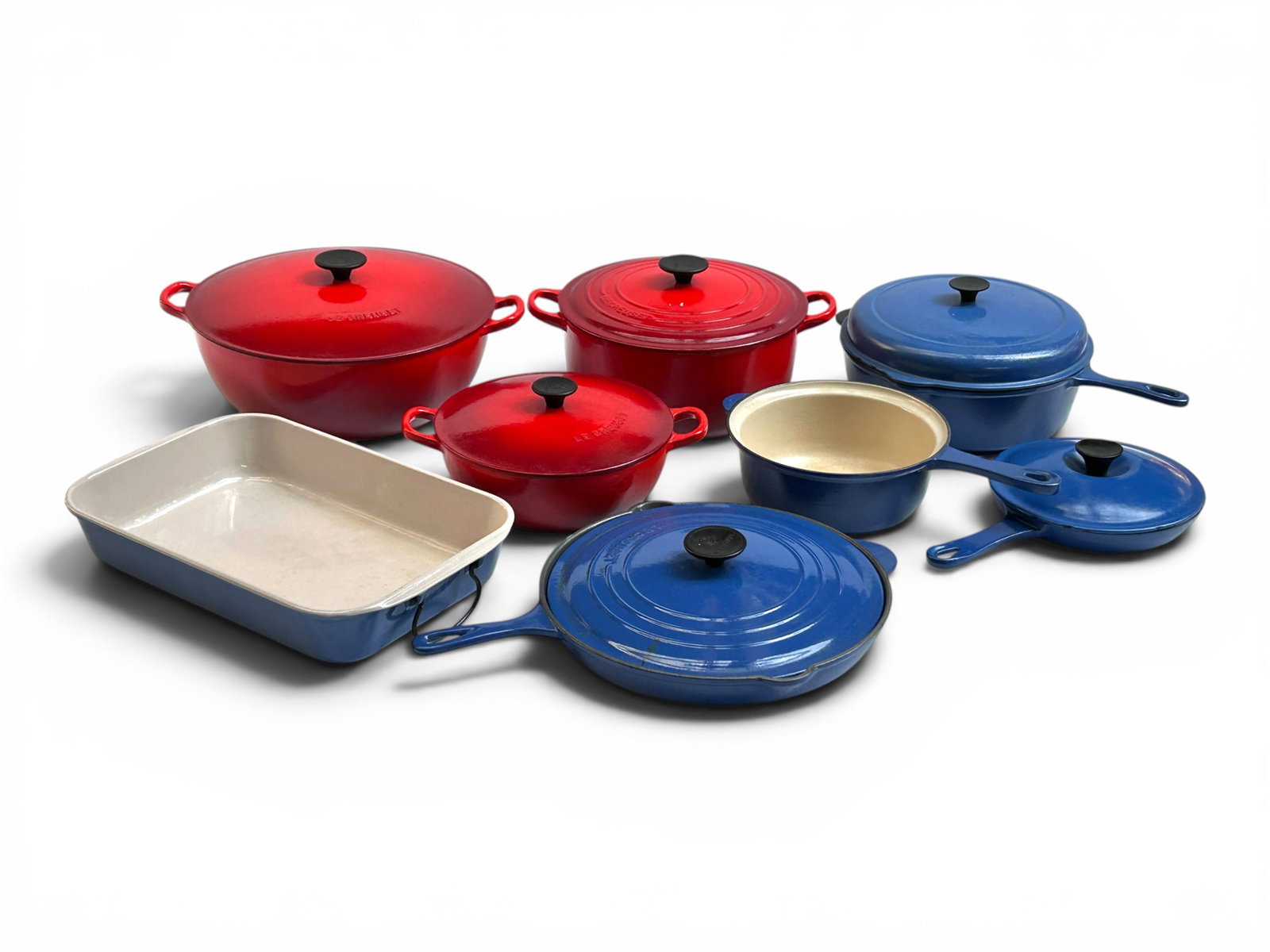 8 Pcs. Blue and Red Le Creuset French Cookware.: The lot contains 8 pieces of Le Creuset France cast iron and enamel cookware, and one extra lid. All but one are vintage, and have the Le Creuset Made in France logo. There are 3 lidded red pots in va