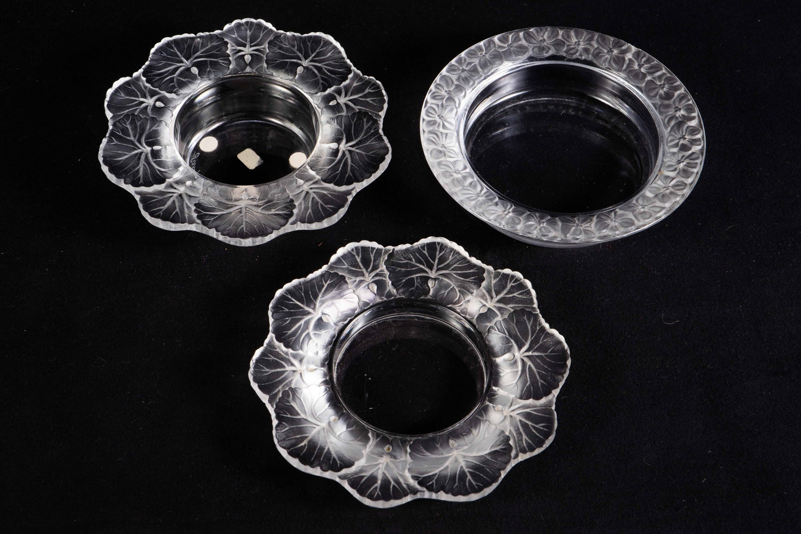 Lot of 3 Lalique France Botanical Bowls.: Two of them are "Honfleur" geranium leaf bowls (one has a chip); the third bowl has a flower border. The largest dish measures 5 7/8" across and 1 3/8" tall. The smallest dish measures 5 7/8" across a