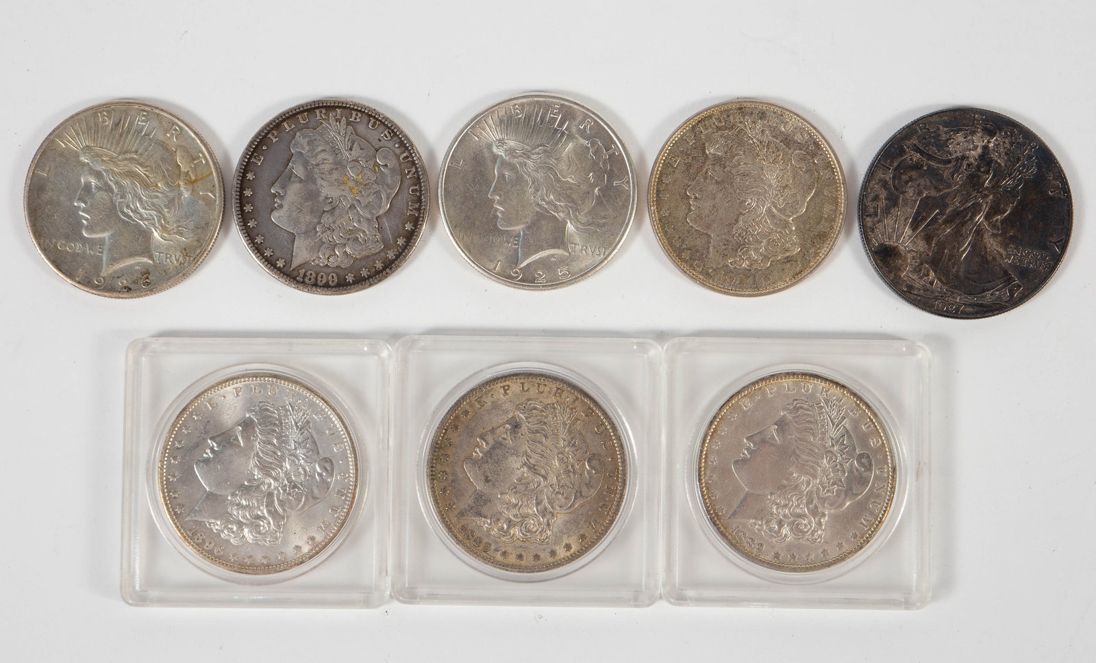 Lot of 7 Silver Dollars & 1 Silver Eagle.: The Morgan silver dollars are as follows: 1896-P (nice condition), 1889-S, 1889-P, 1899-S (toned), and 1921-P. The Silver Eagle is heavily tarnished or toned. It is a 1987-P. The Peace Dollars are 192