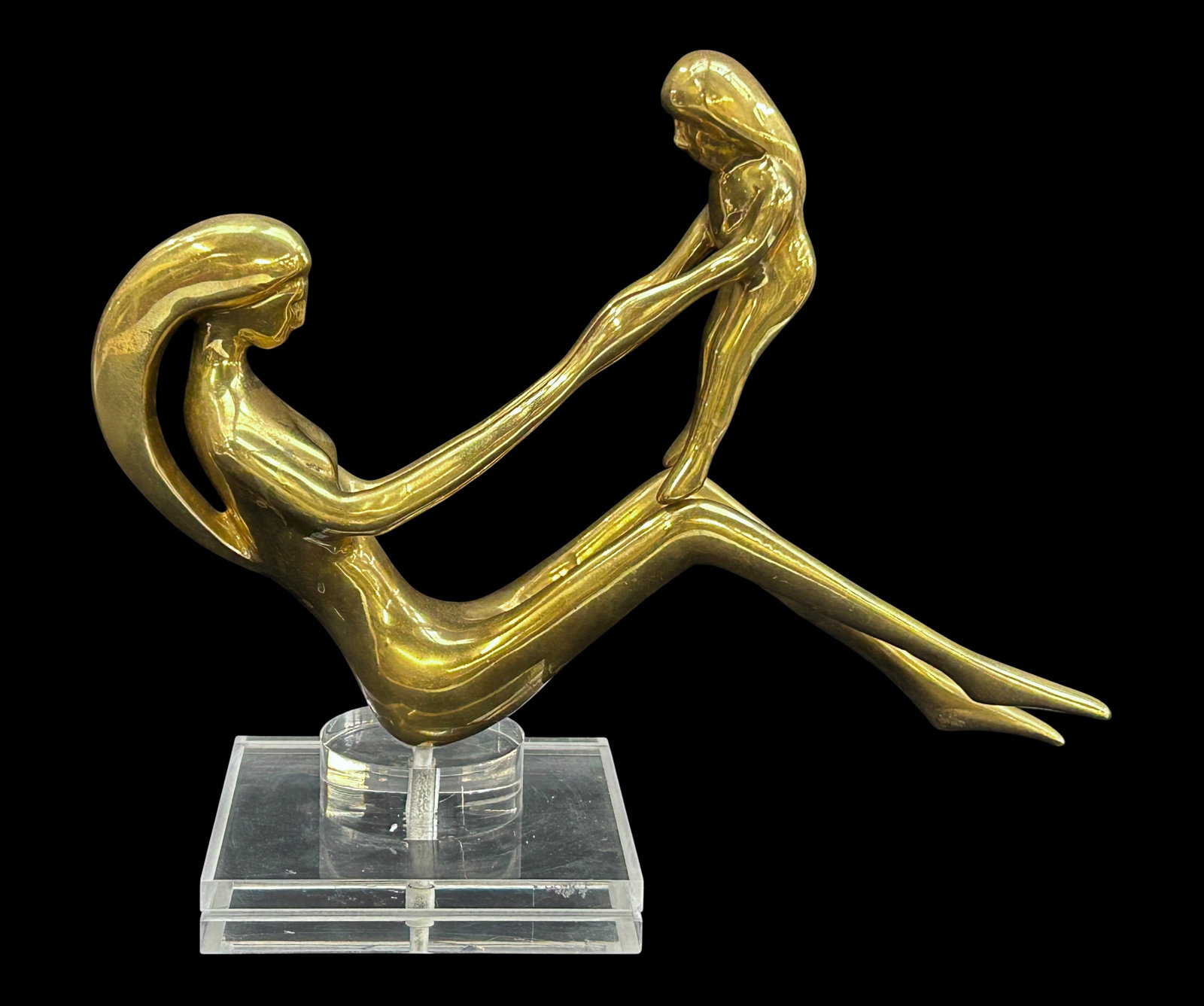MCM Polished Brass Sculpture of Mother & Daughter.: The unsigned mid-century modern figural sculpture is on a Lucite base. It depicts a mother and daughter in play. It measures 11" tall, 13 3/4" wide, and 5 1/2" deep (including base). There are some sc