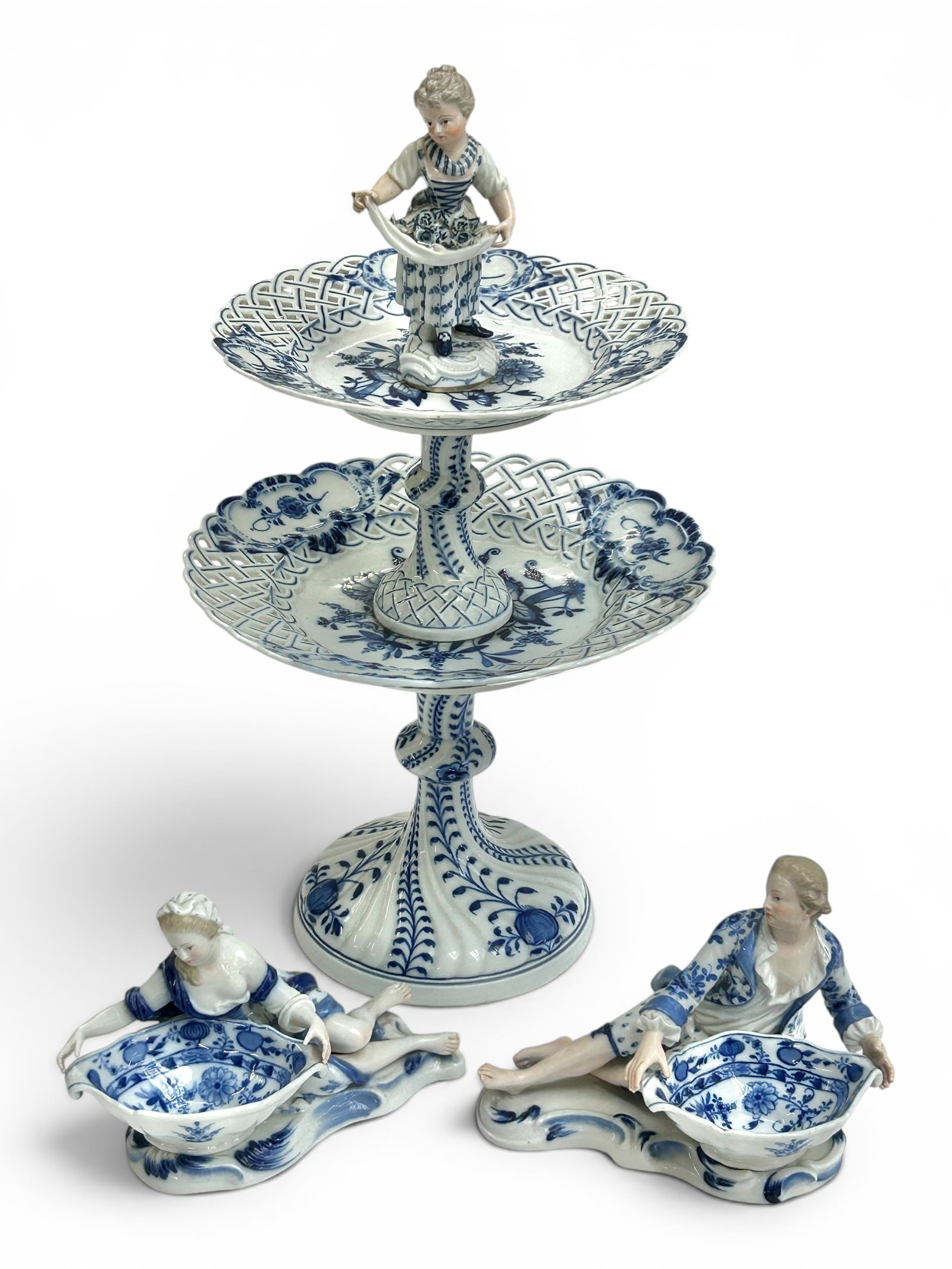 Meissen Blue Onion Dessert Stand, Sweetmeat Dishes: The lot contains 3 Meissen blue onion porcelain pieces. There is a two tier dessert stand with a female figure holding roses in her apron on the top. It measures 16 3/8" tall, and up to 9 3/8" in diam