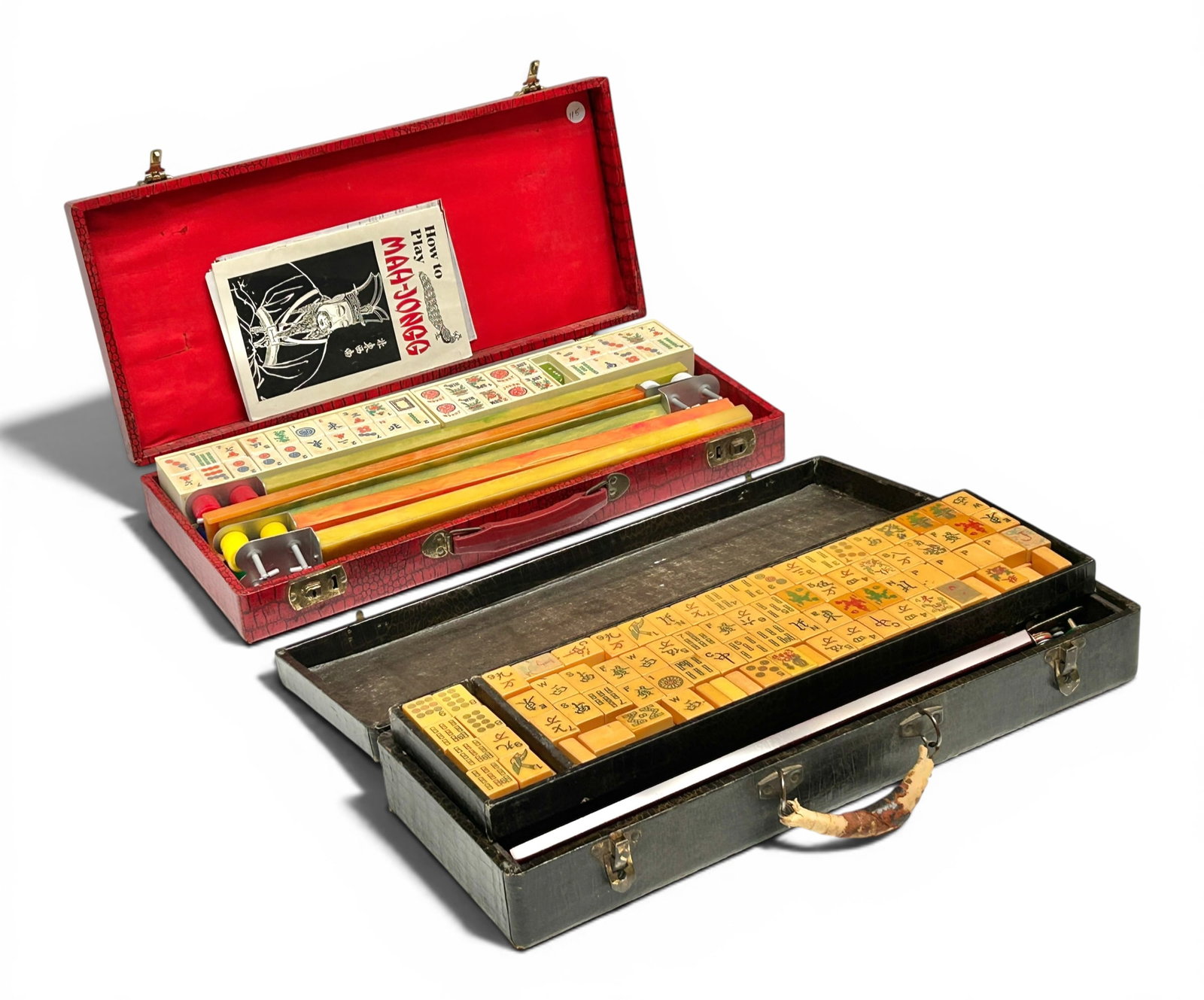 2 Bakelite Mah Jongg Sets in Cases inc. Crisloid.: The lot contains 2 vintage mah jongg sets in carrying cases. The red case is by Crisloid, and comes with white bakelite chips, 5 bakelite racks, counters, and some manuals. The chips include Jokers. T