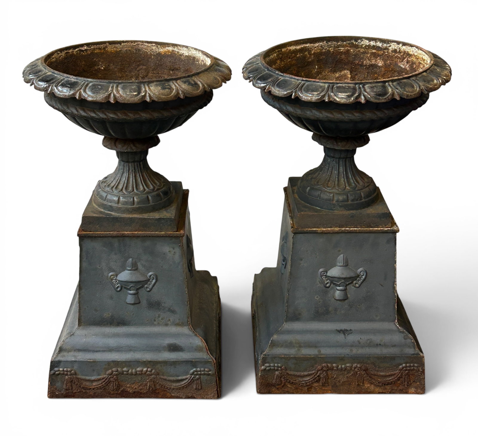 Pair of Old Cast Iron Garden Urns.: These sculpted urns or planters sit on stands that are adorned with decorations on the sides. There is some rust, as well as scratches and indentations. Overall, they are in good condition. The tops