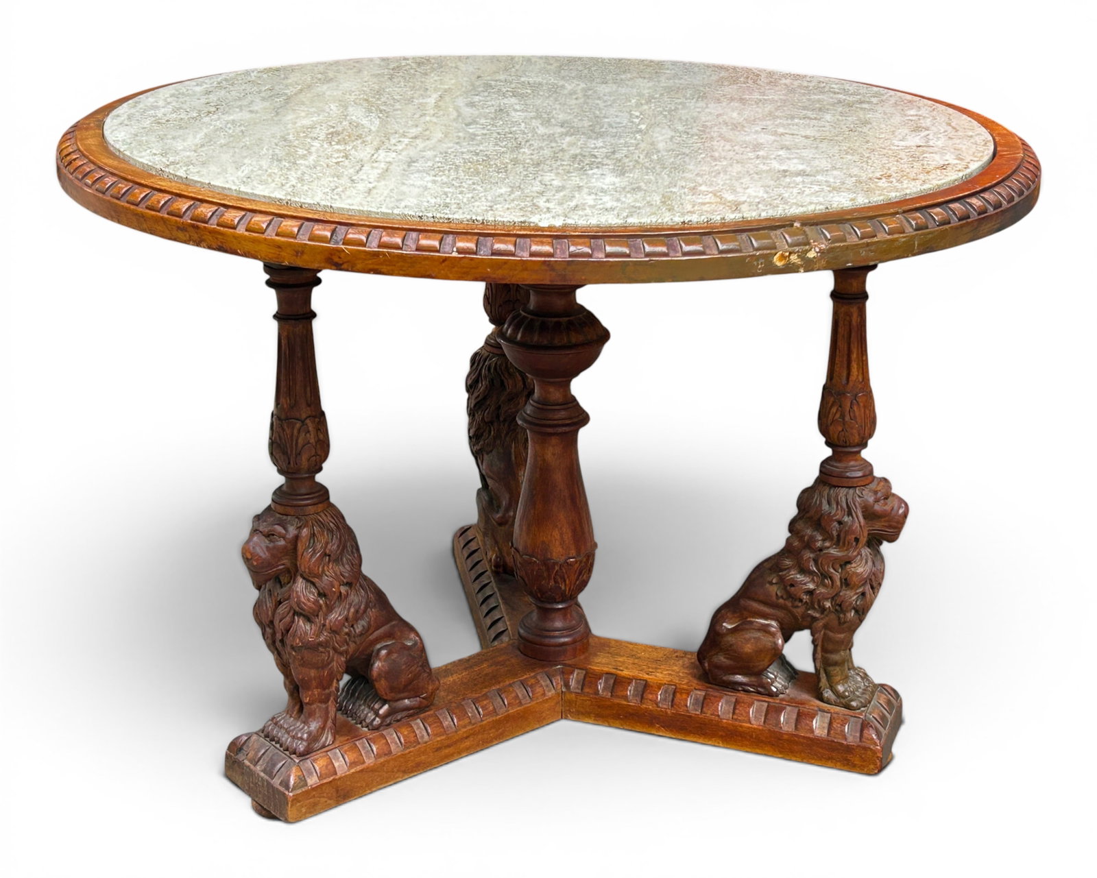 Antique Carved Table with Lions.: This antique walnut coffee table has a travertine top, carved lions, and columns. Etched into the wood supports is "7094/181 1914." The travertine top has a chip, and there is a small damaged area on 