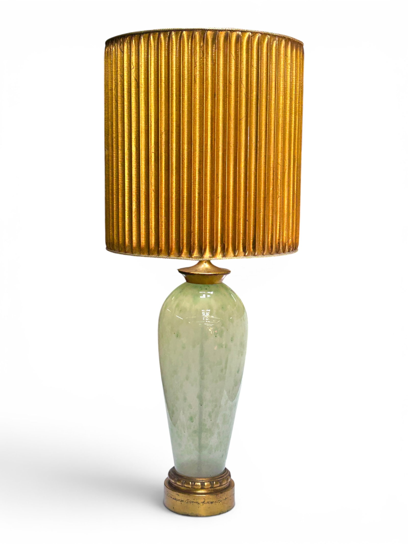 Hollywood Regency Style Jade Glass Gilt Table Lamp: The massive table lamp has a seemingly reverse painted light jade green colored glass base with a gilded bottom and a ribbed gilded shade. It measures 43 1/2" tall, and up to 18 1/2" in diameter. The 