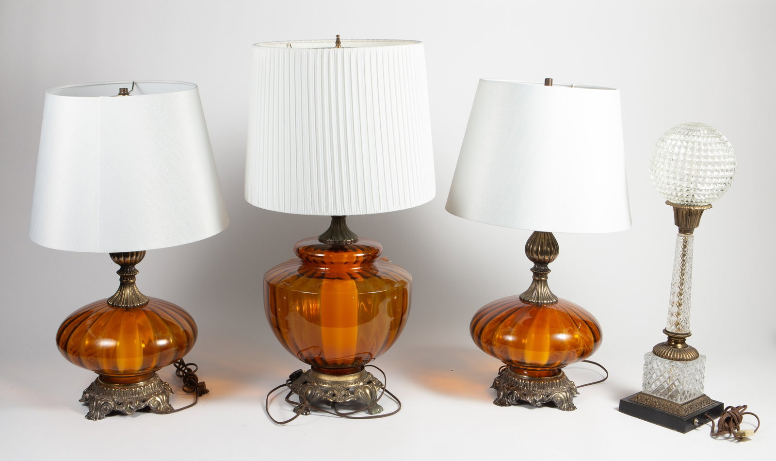 Lot of 3 Amber Glass Table Lamps- 2 Are a Pair.: These lamps have bronzelike bases (actually white metal) and amber colored glass bodies. The two smaller lamps are a pair. Overall, the lot looks to be in good condition. The larger lamp measures 11 1
