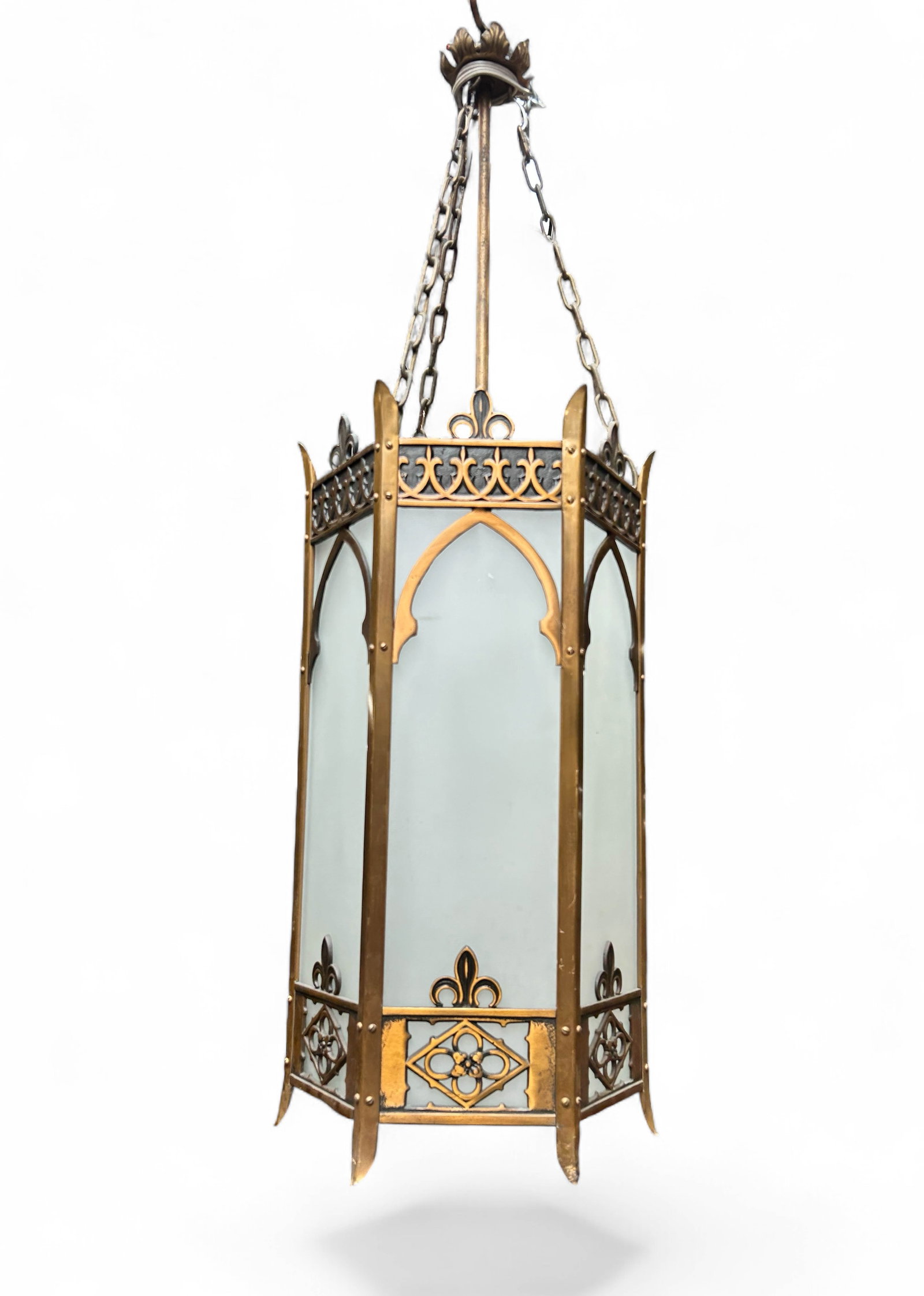 Gothic Style Bronze ? Glass Pendant Light.: The hexagonal pendant light has a wrought and cast bronze or bronze finish frame and frosted glass panels on the 6 sides and the bottom. It has a post, 3 chains, and an ornate bale. The lamp itself