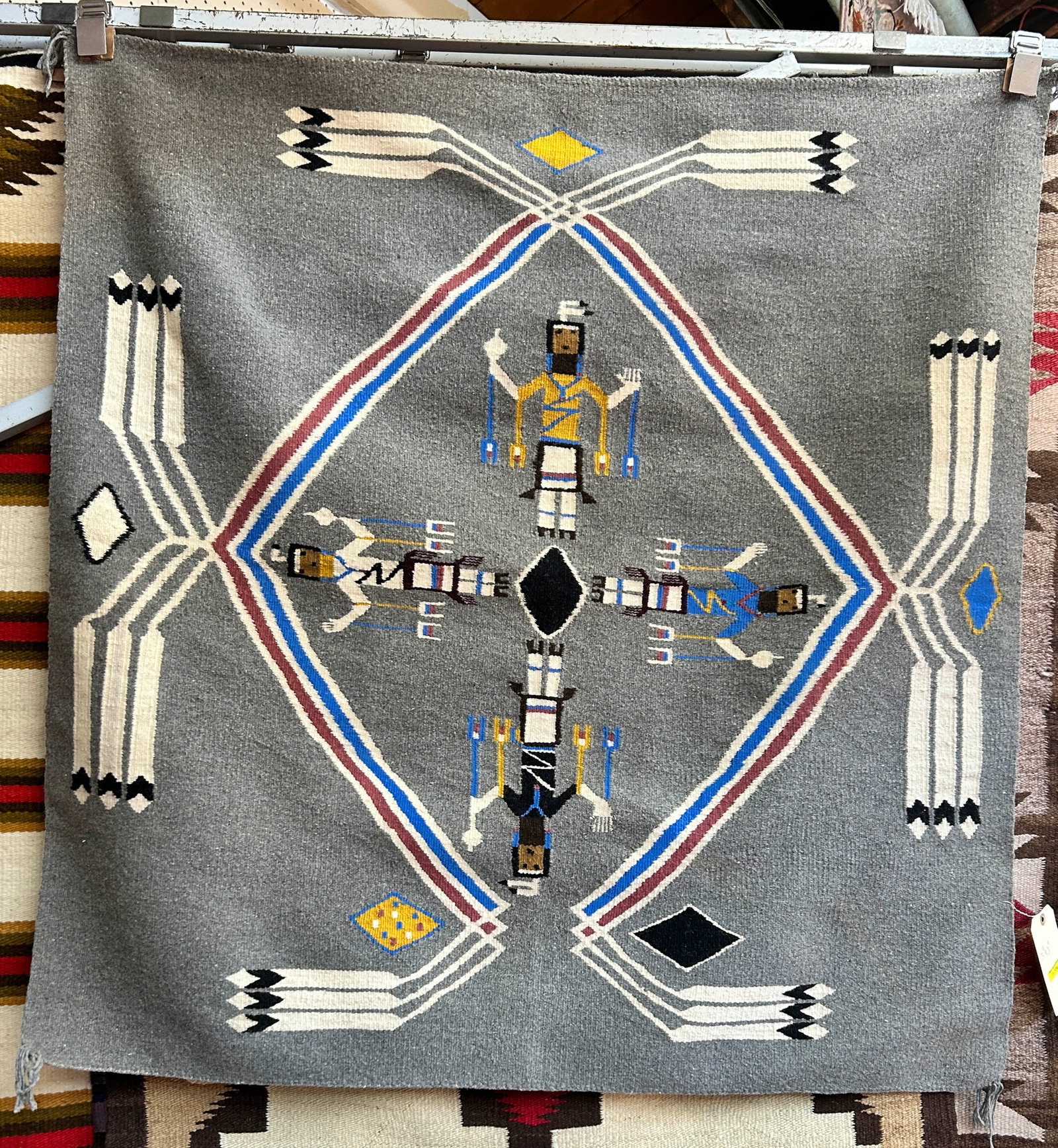 3' 9" x 3' 11" Grey Navajo Rug w/ Figures.: The rug has 4 Native American Indian men in the center. It looks to be in good condition. It is a bit on the newer side. In-House Shipping is available for this rug. Please see our website for our in-